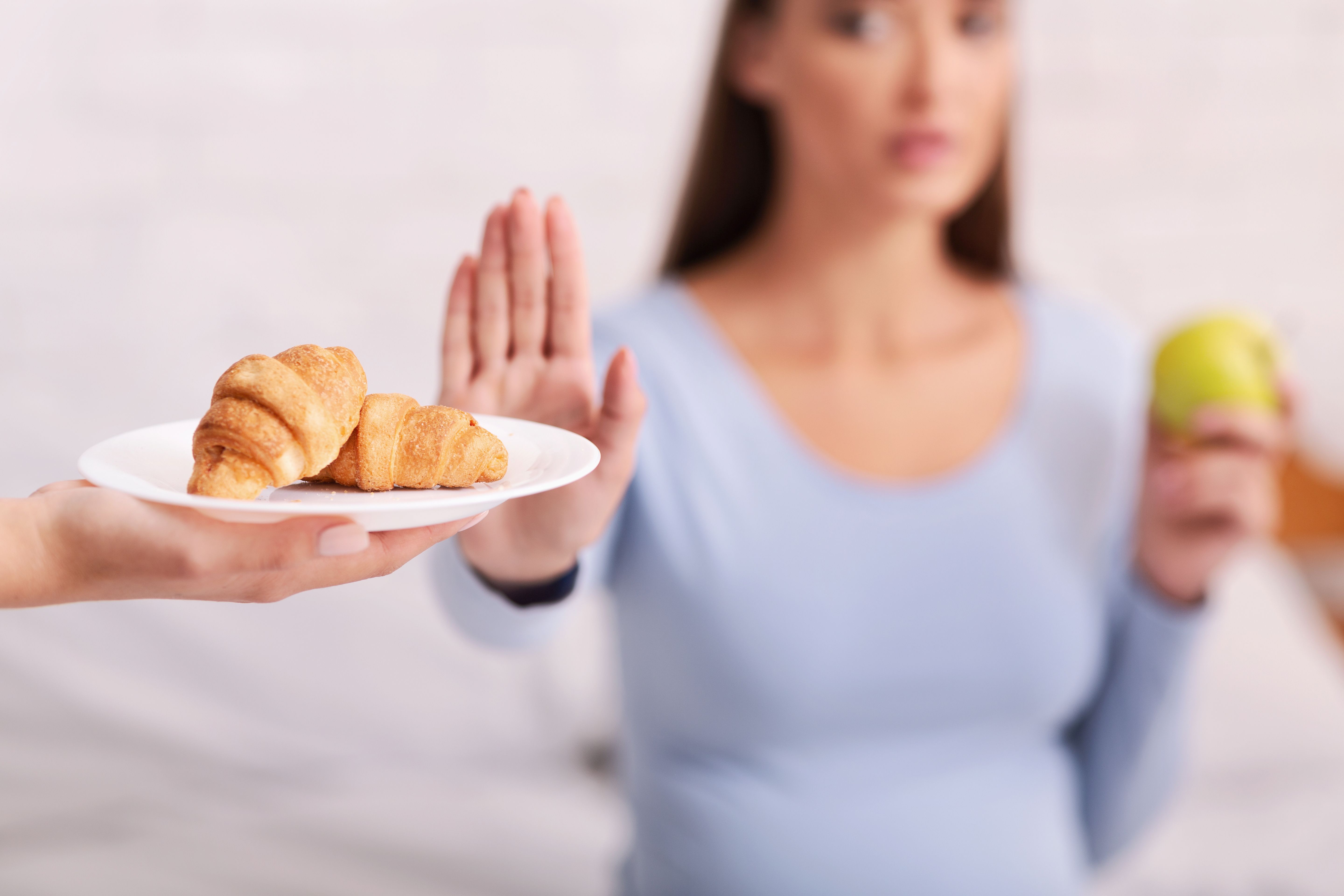 Pregnant Woman Choosing Apple Instead Of Croissants Sitting On Bed