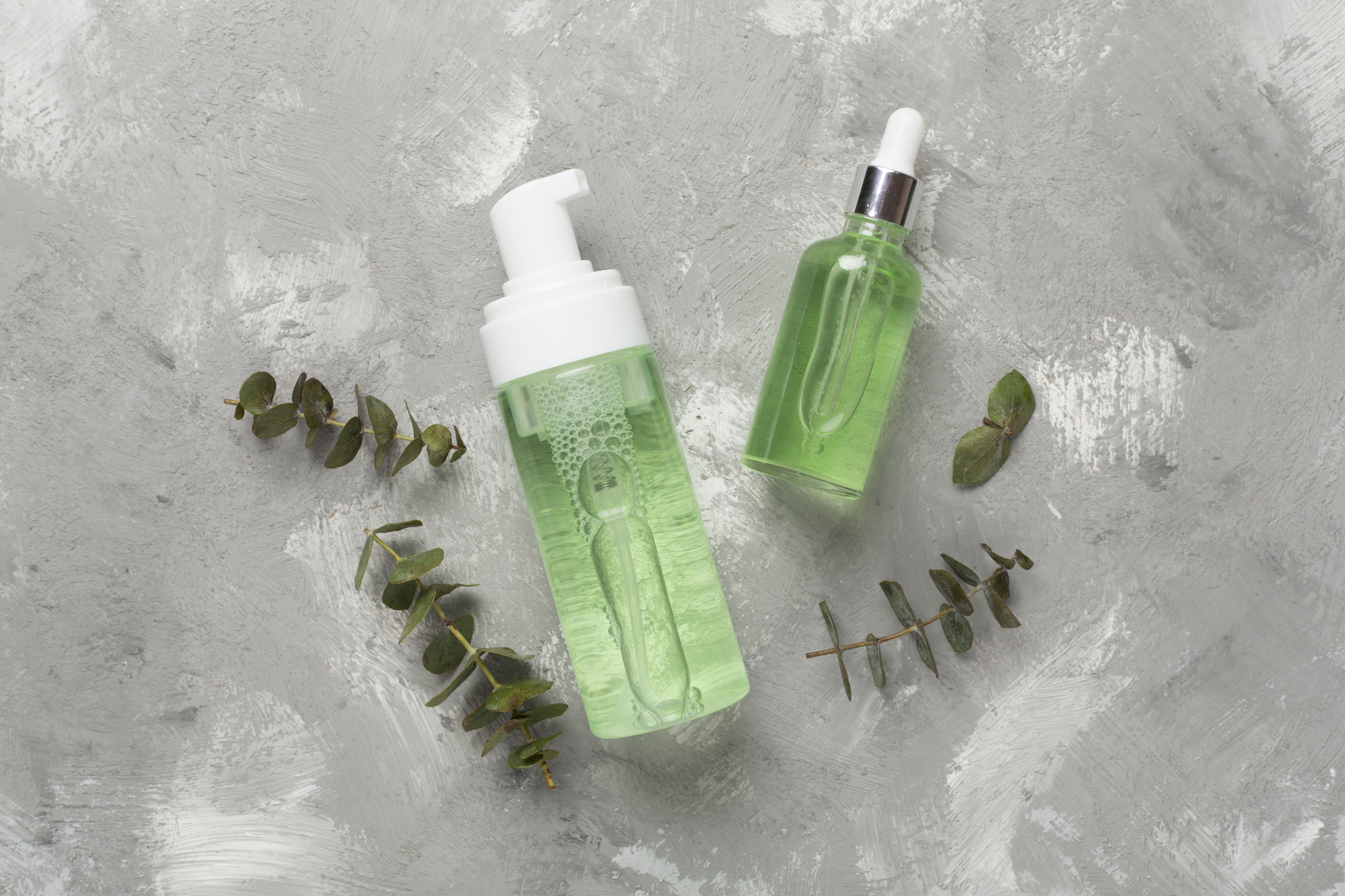 Herbal face care products on concrete background, top view