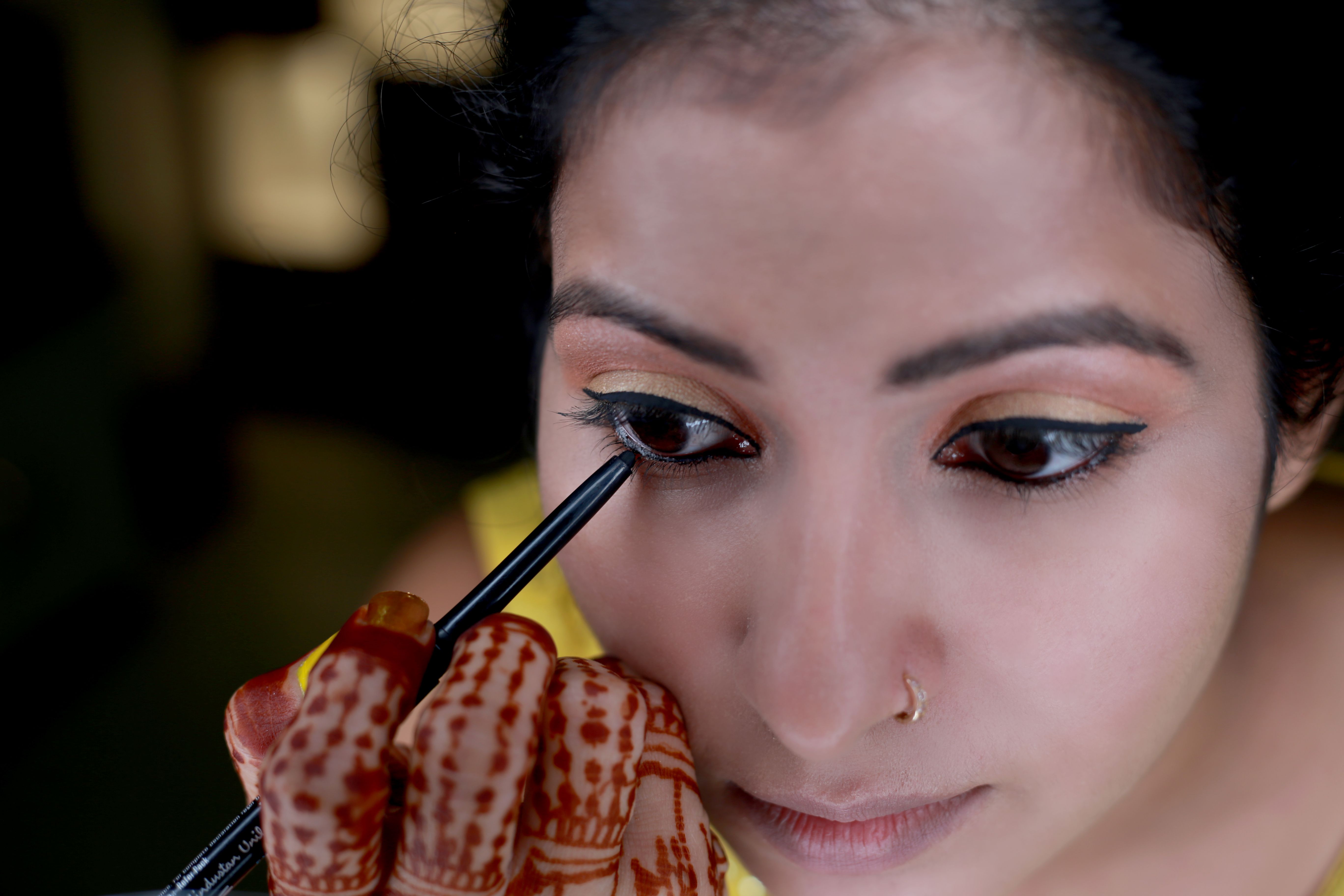 Women applying kohl in eyes