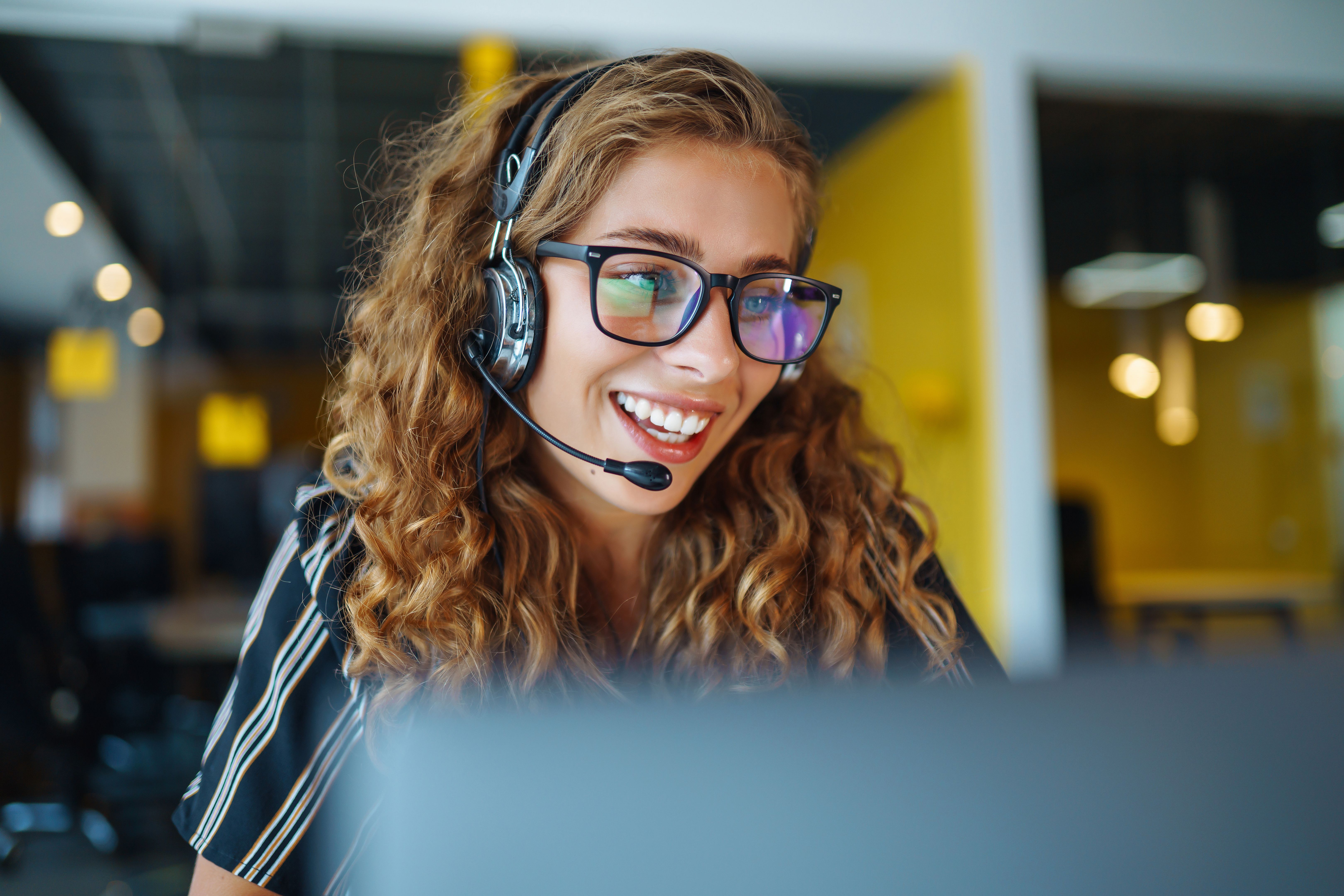 Young operator woman with headsets working in a call centre.