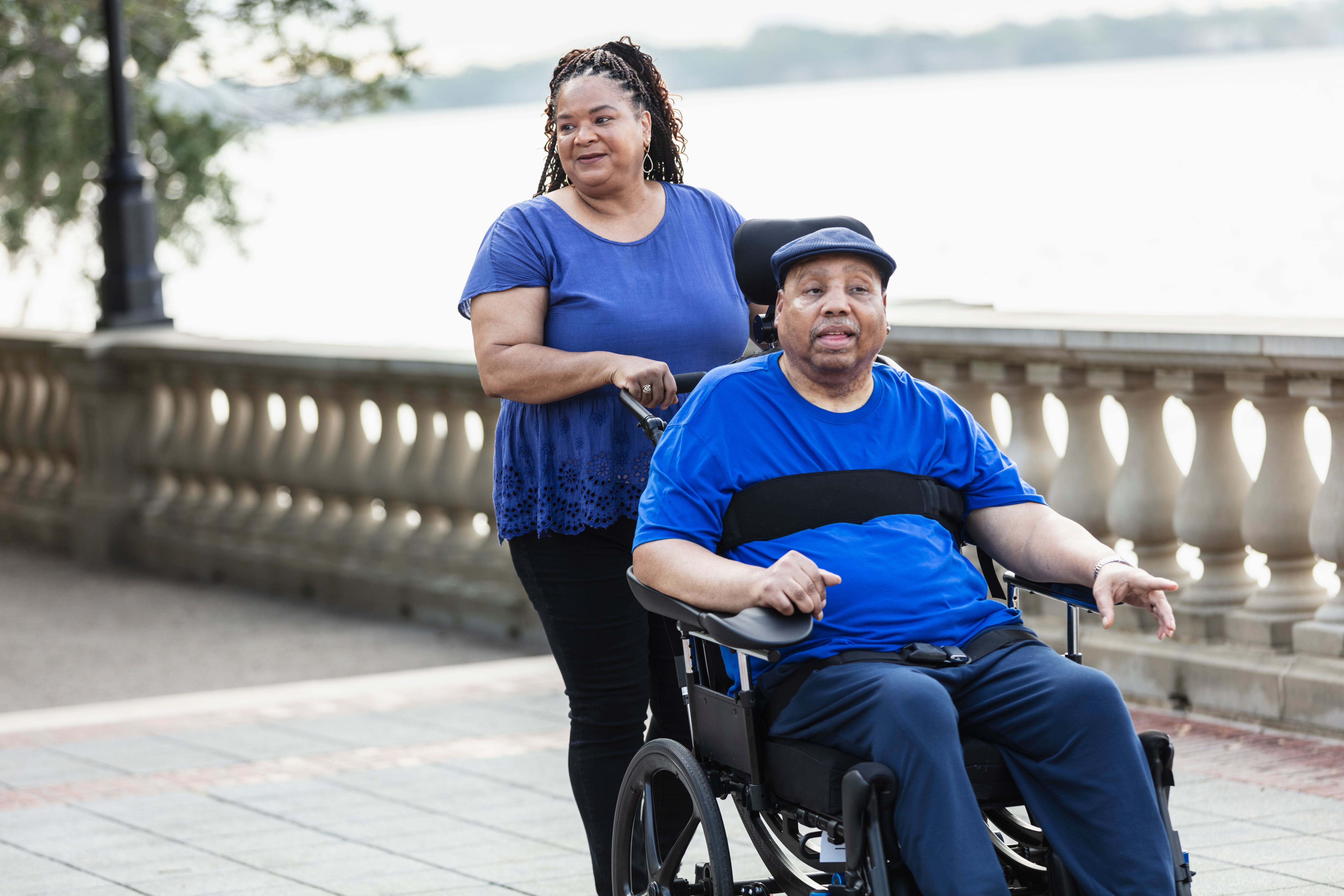 Senior African-American couple on walk, with wheelchair Senior African-American couple on walk, with wheelchair