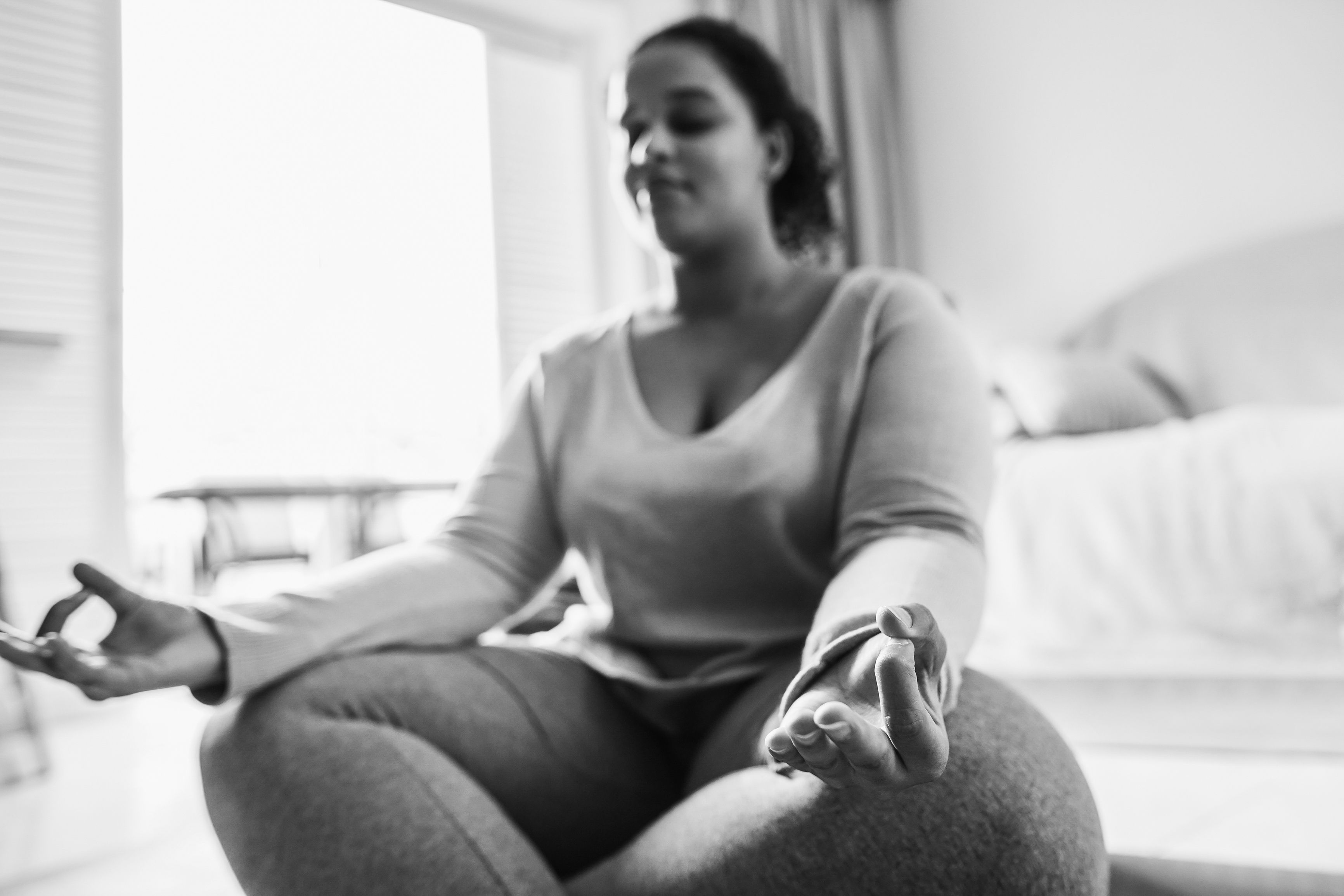 African curvy girl doing yoga exercises at home during winter time - Focus on right hand - Black and white editing African curvy girl doing yoga exercises at home during winter time - Focus on right hand - Black and white editing