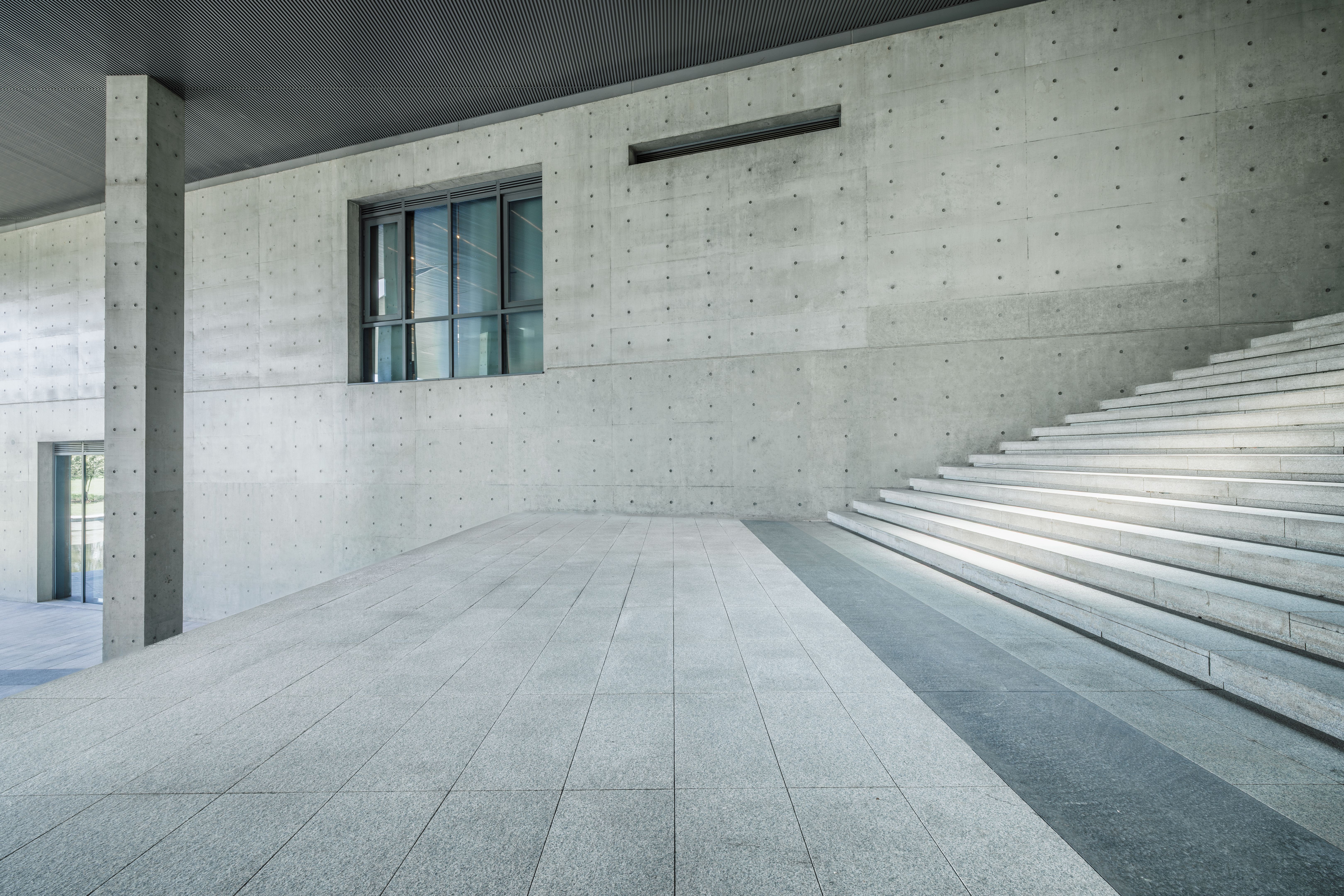 Modern building exterior with concrete wall, staircase and empty floor.