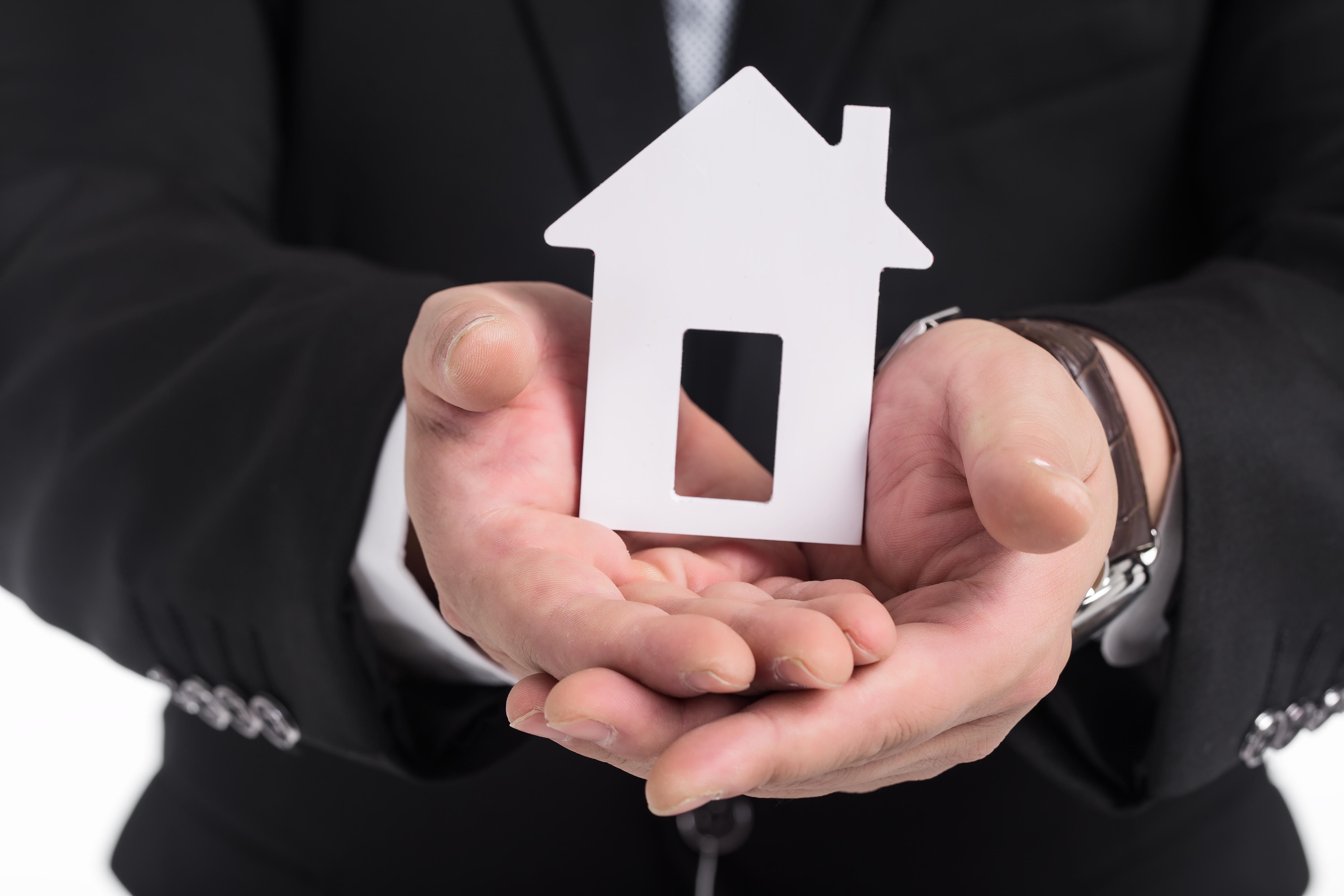 Real estate agent holding a paper house in his hands