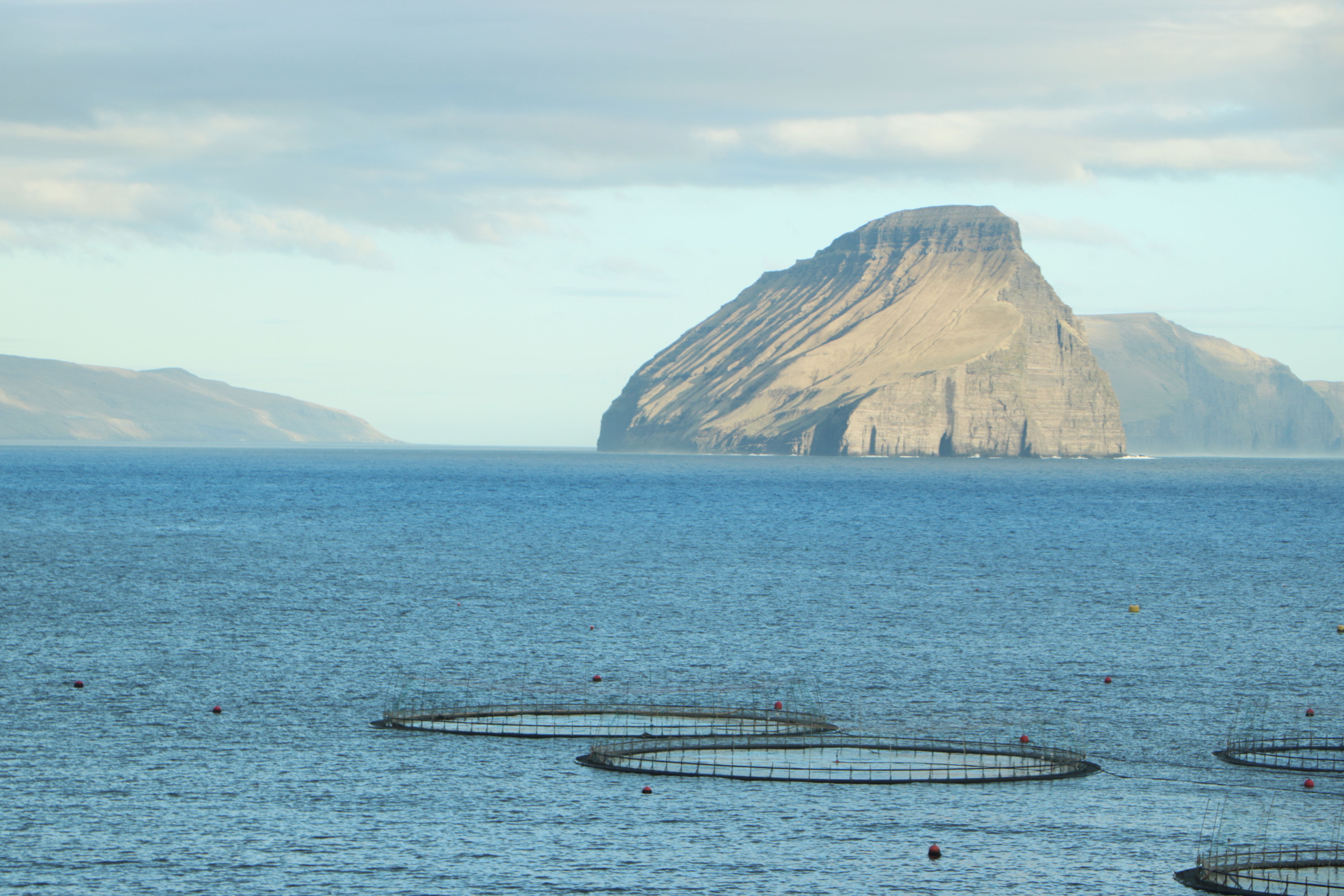 Scenic view of a mountain island with fish farming cages in Faroe Islands