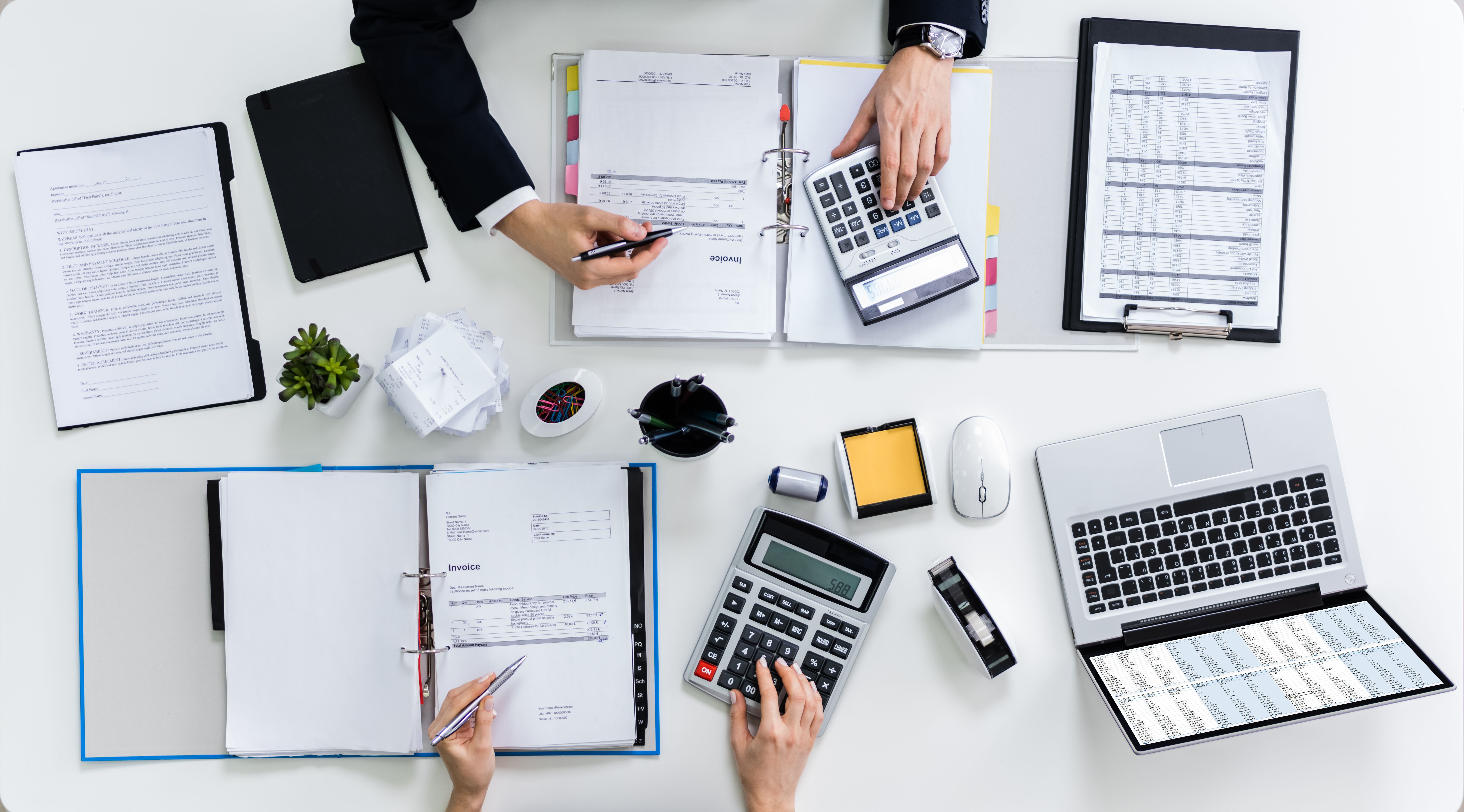 Two Businesspeople Calculating Bills In Office
