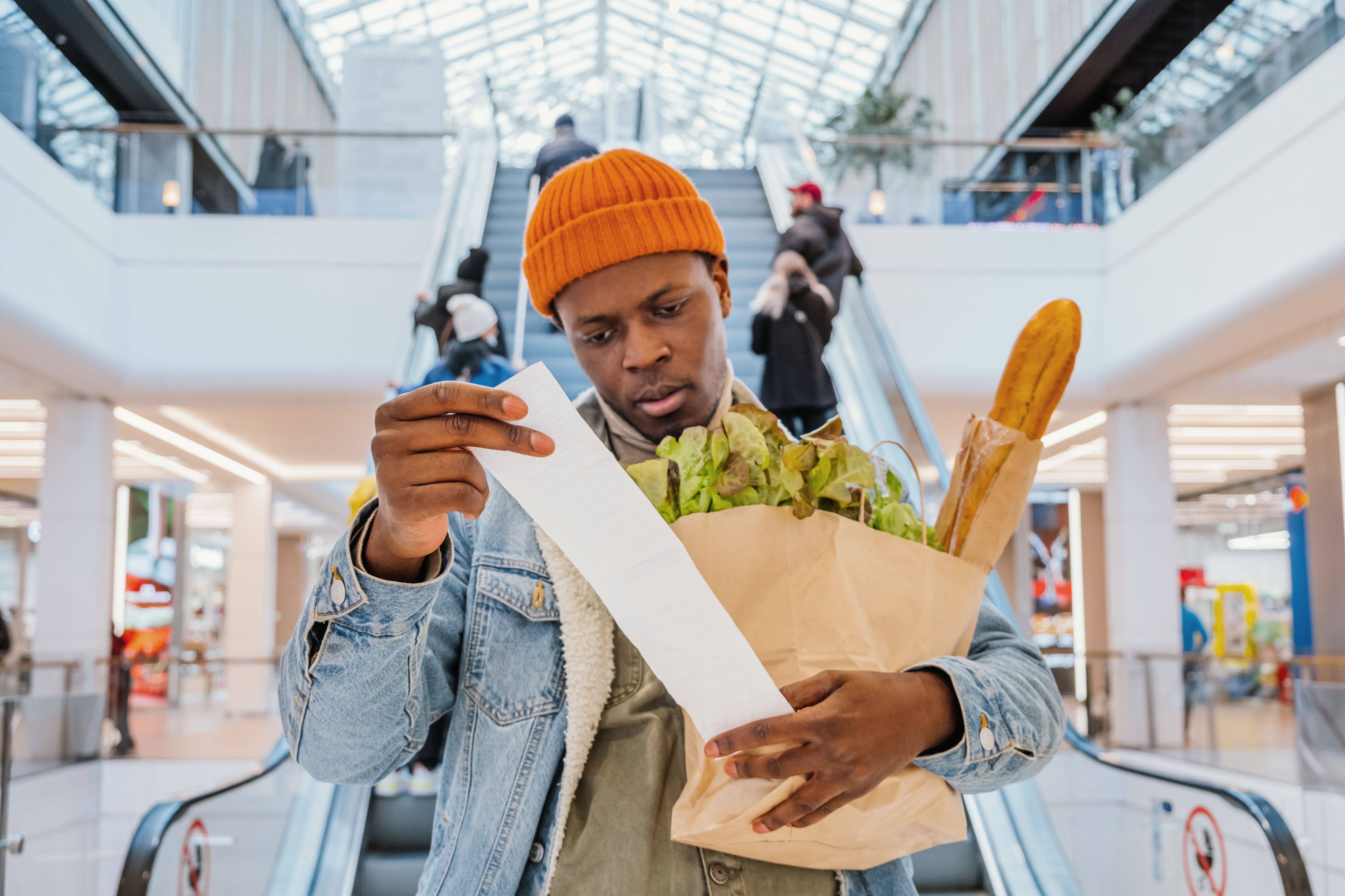 Surprised black man looks at receipt total with food in mall Surprised black man looks at receipt total with food in mall