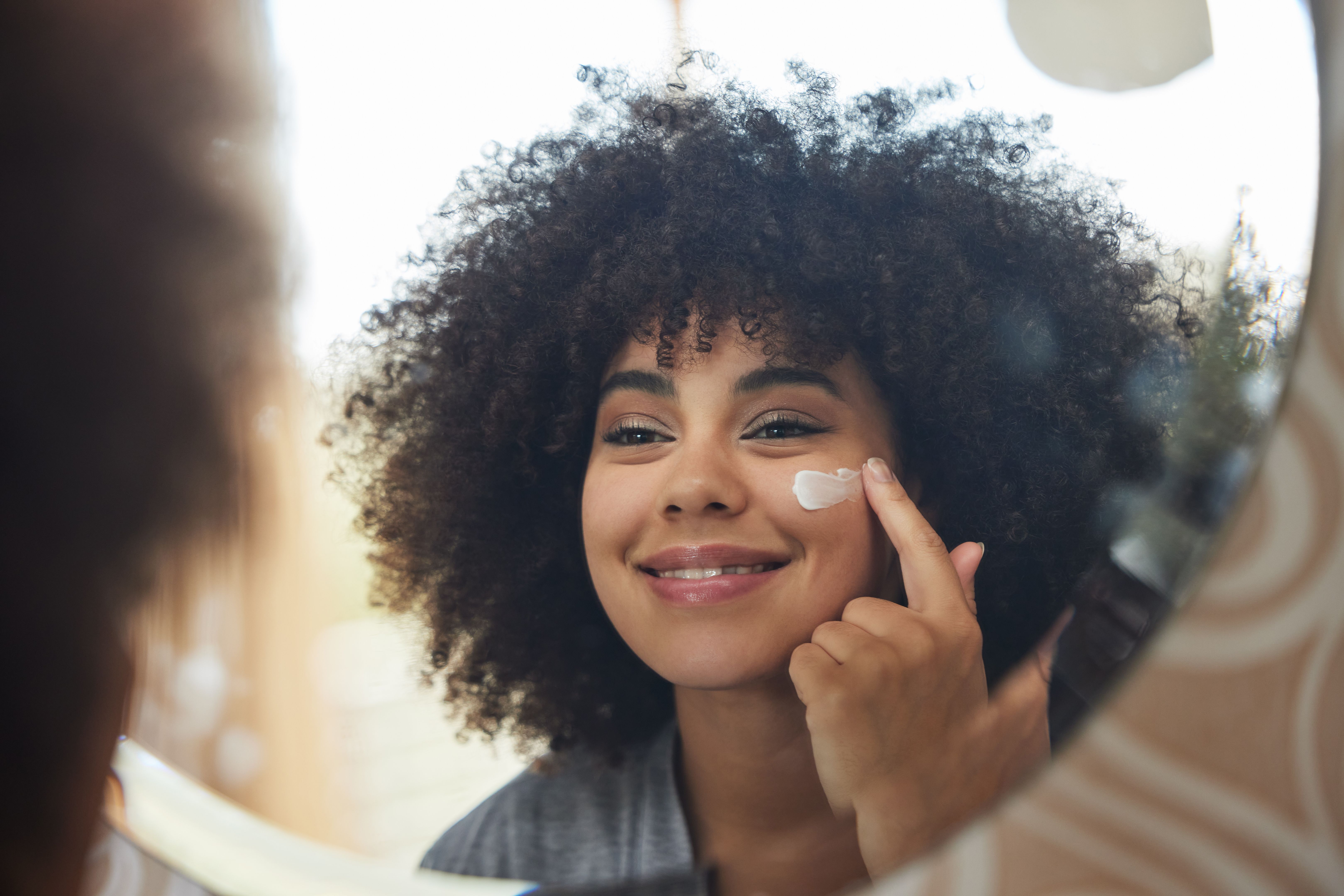 Shot of an attractive young woman applying moisturiser to her face at home Shot of an attractive young woman applying moisturiser to her face at home