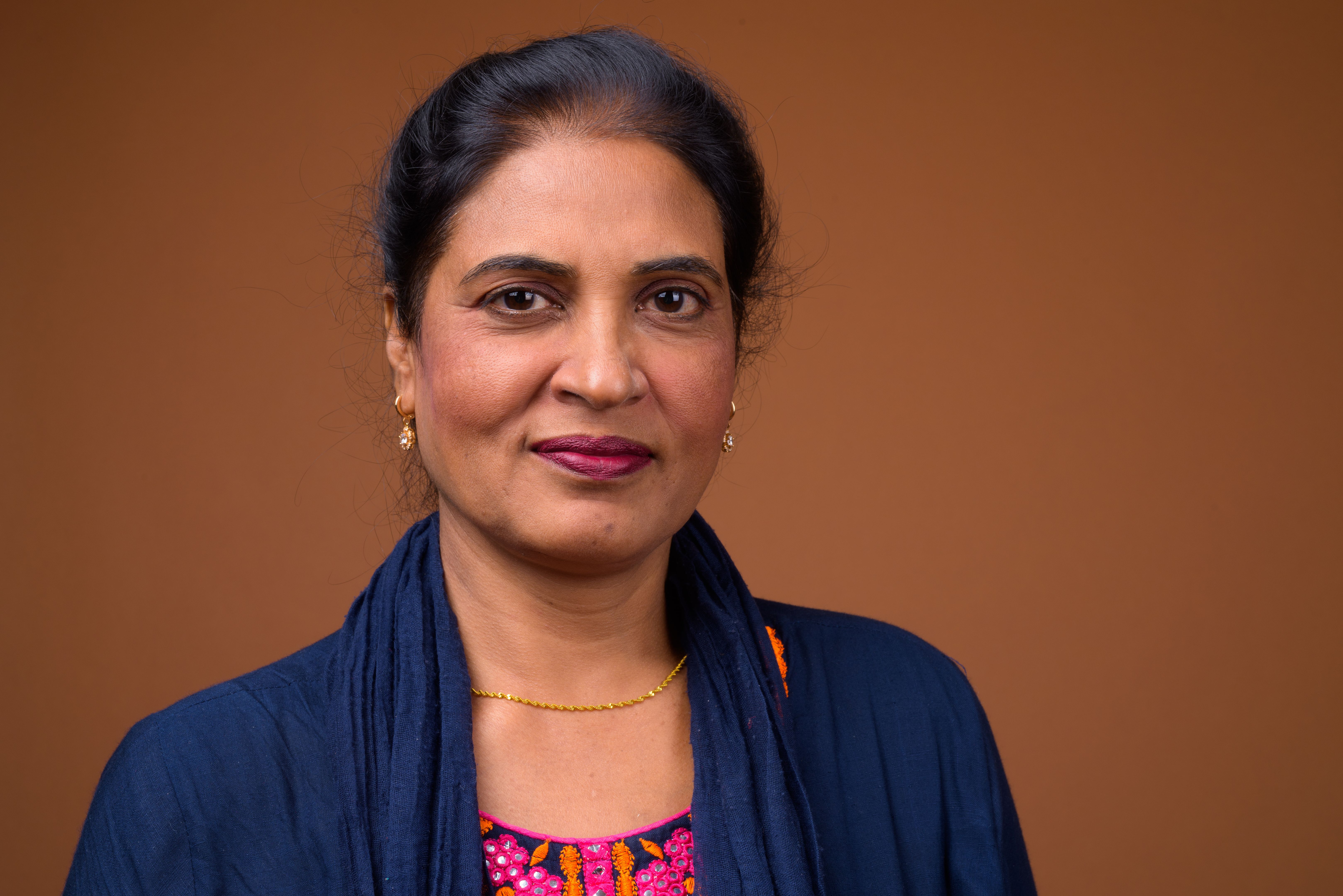 Studio shot of mature beautiful Indian woman against colored background