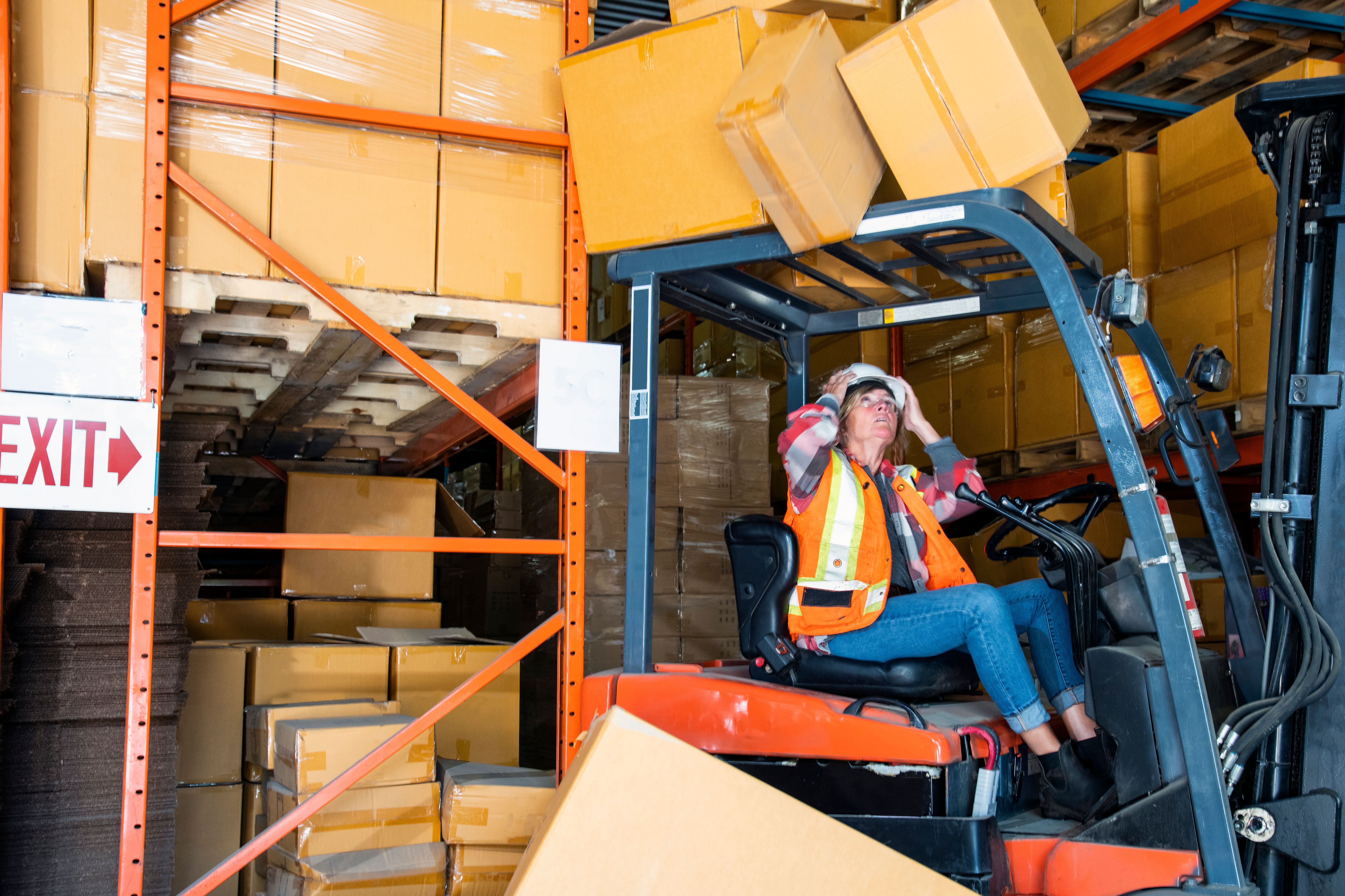 A warehouse forklift safety topic.  A forklift driver reverses into a shelf knocking boxes of that fall onto the forklift.