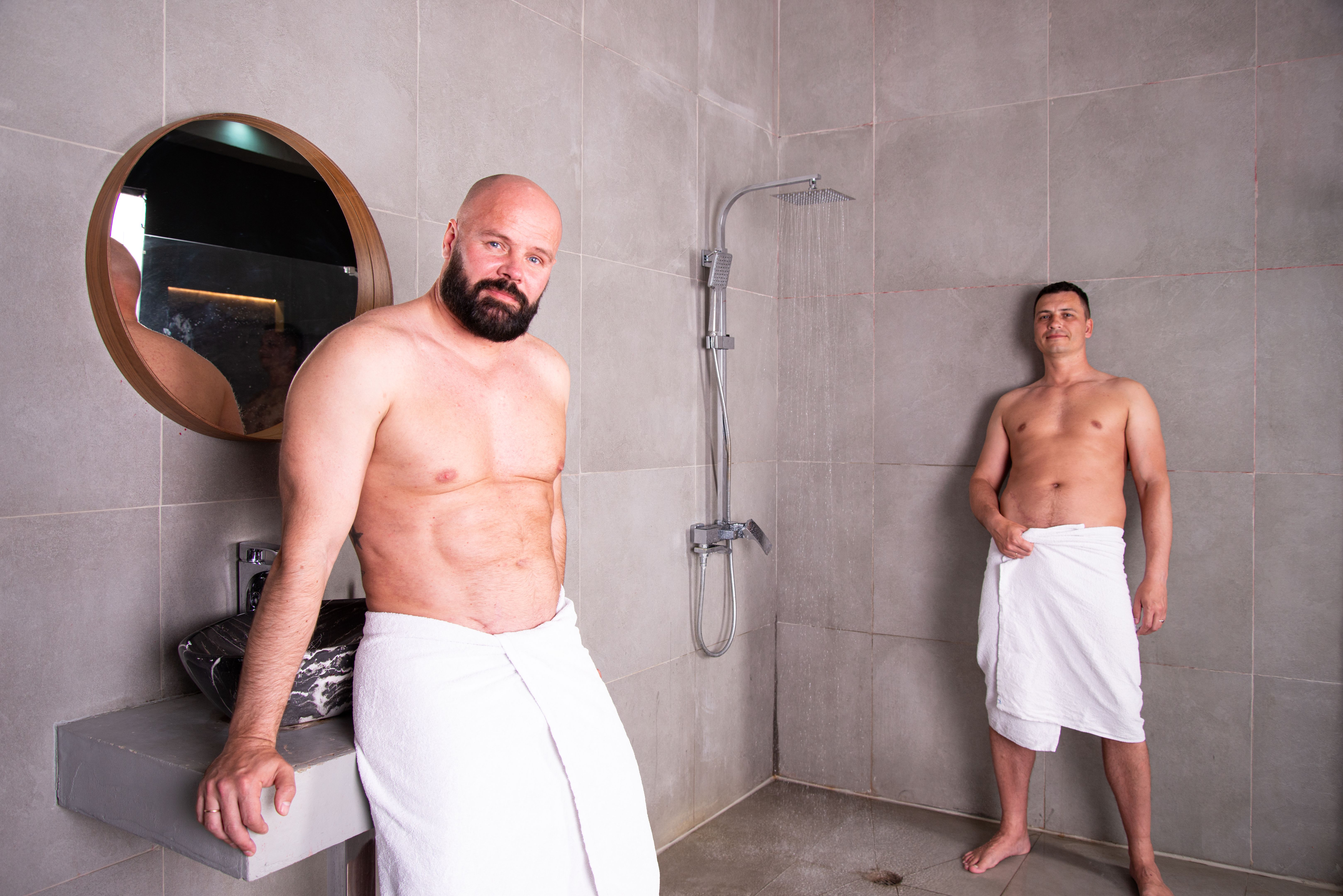 An attractive adult gay couple washes in the shower together. Love and relationship between two men. An attractive adult gay couple washes in the shower together. Love and relationship between two men.