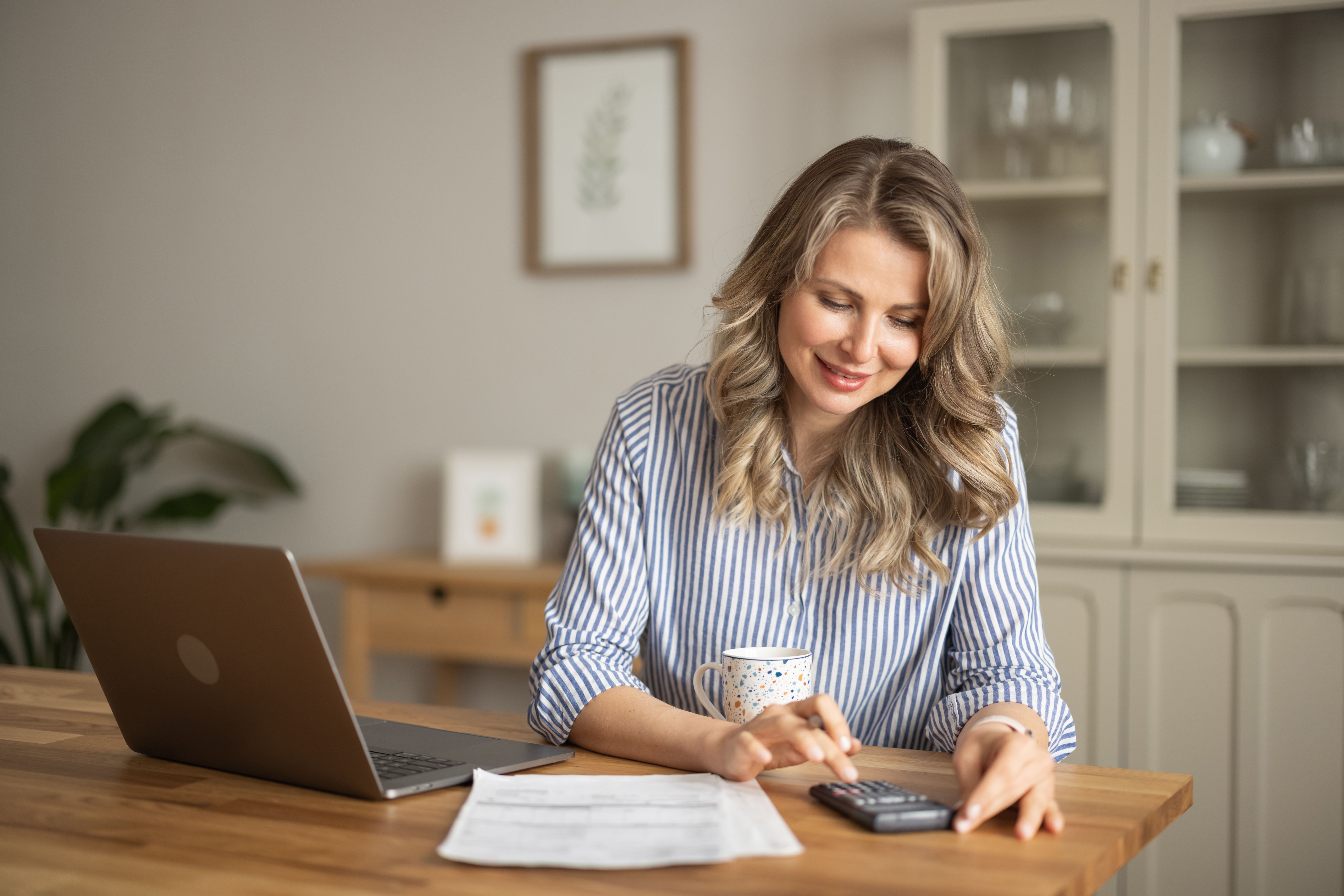 Woman manage household finances in kitchen Woman manage household finances in kitchen