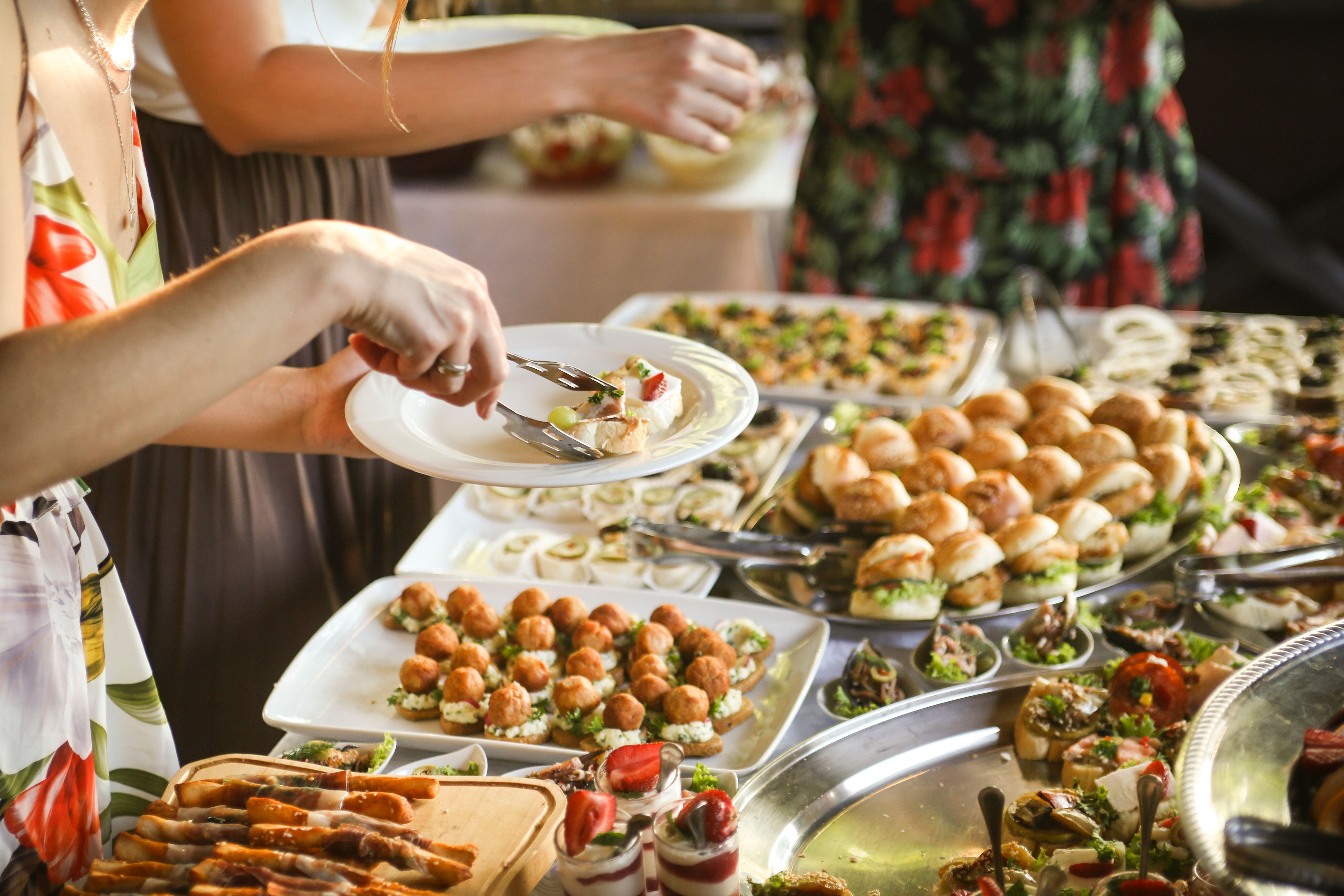 People choosing food from a buffet table People choosing food from a buffet table