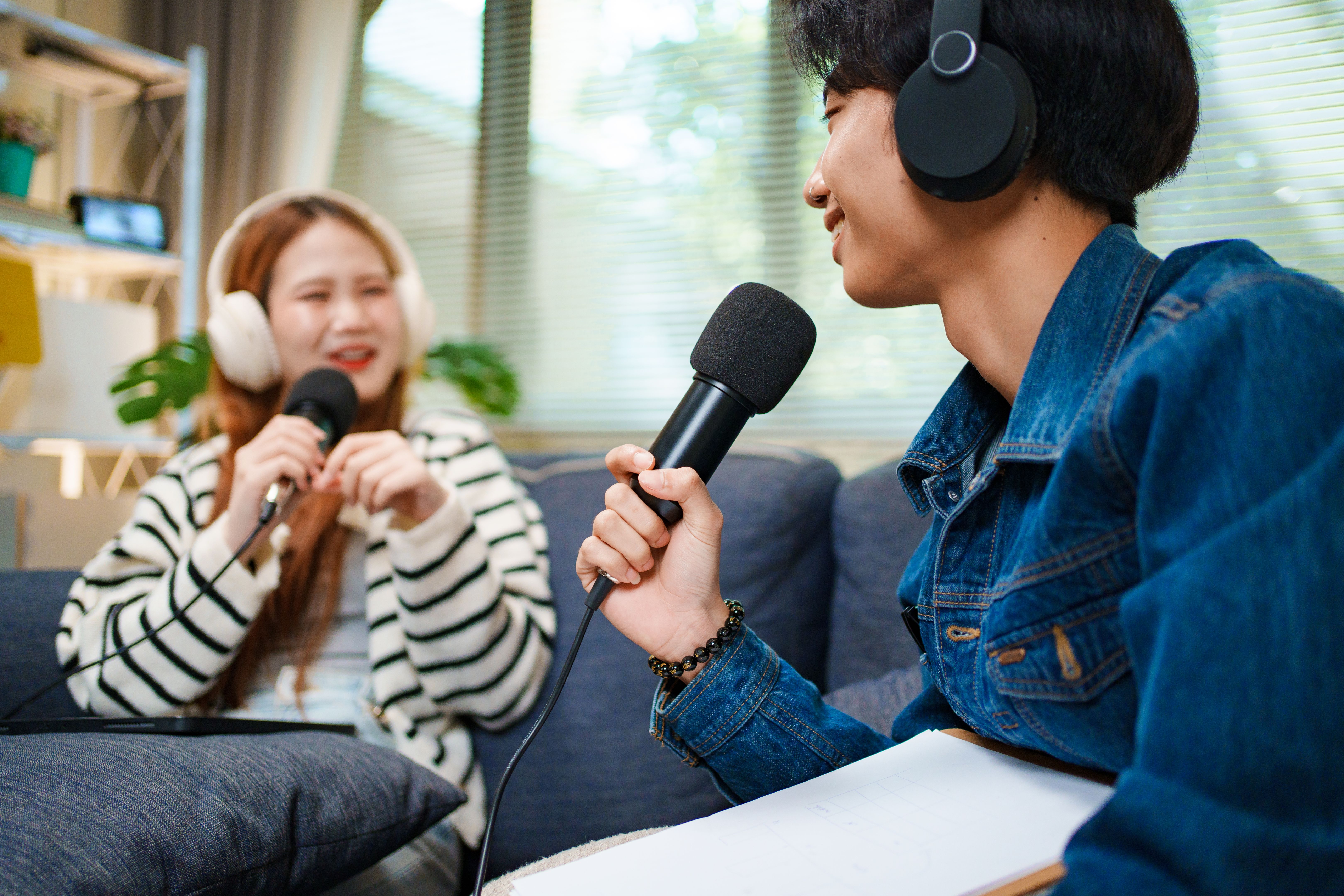 Young man speaking in podcast with headphones and microphone at home