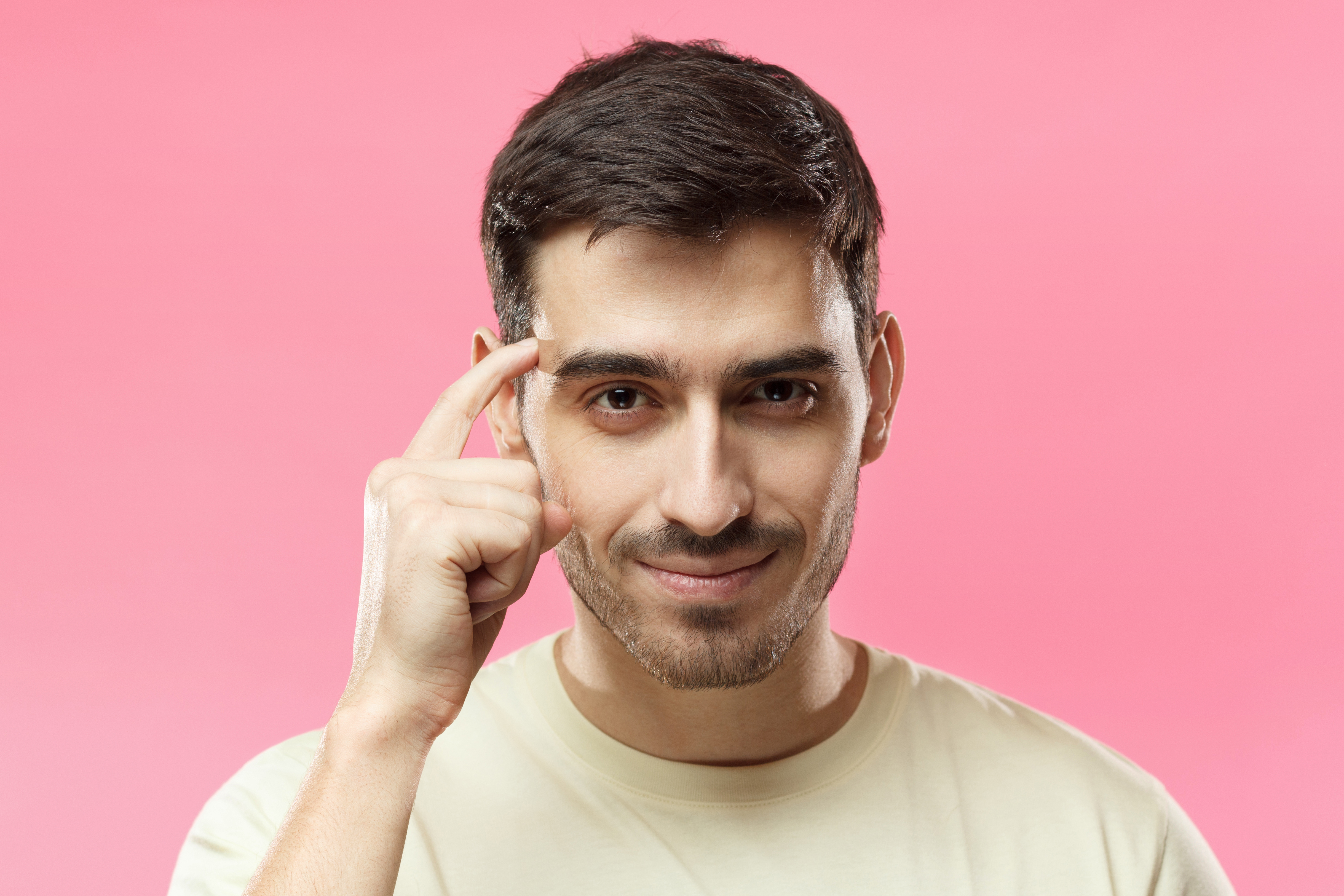 Closeup portrait of young European Caucasian man pictured isolated on pink background pressing finger to temple as if making viewer think more about offer or analyze information better for their good Closeup portrait of young European Caucasian man pictured isolated on pink background pressing finger to temple as if making viewer think more about offer or analyze information better for their good