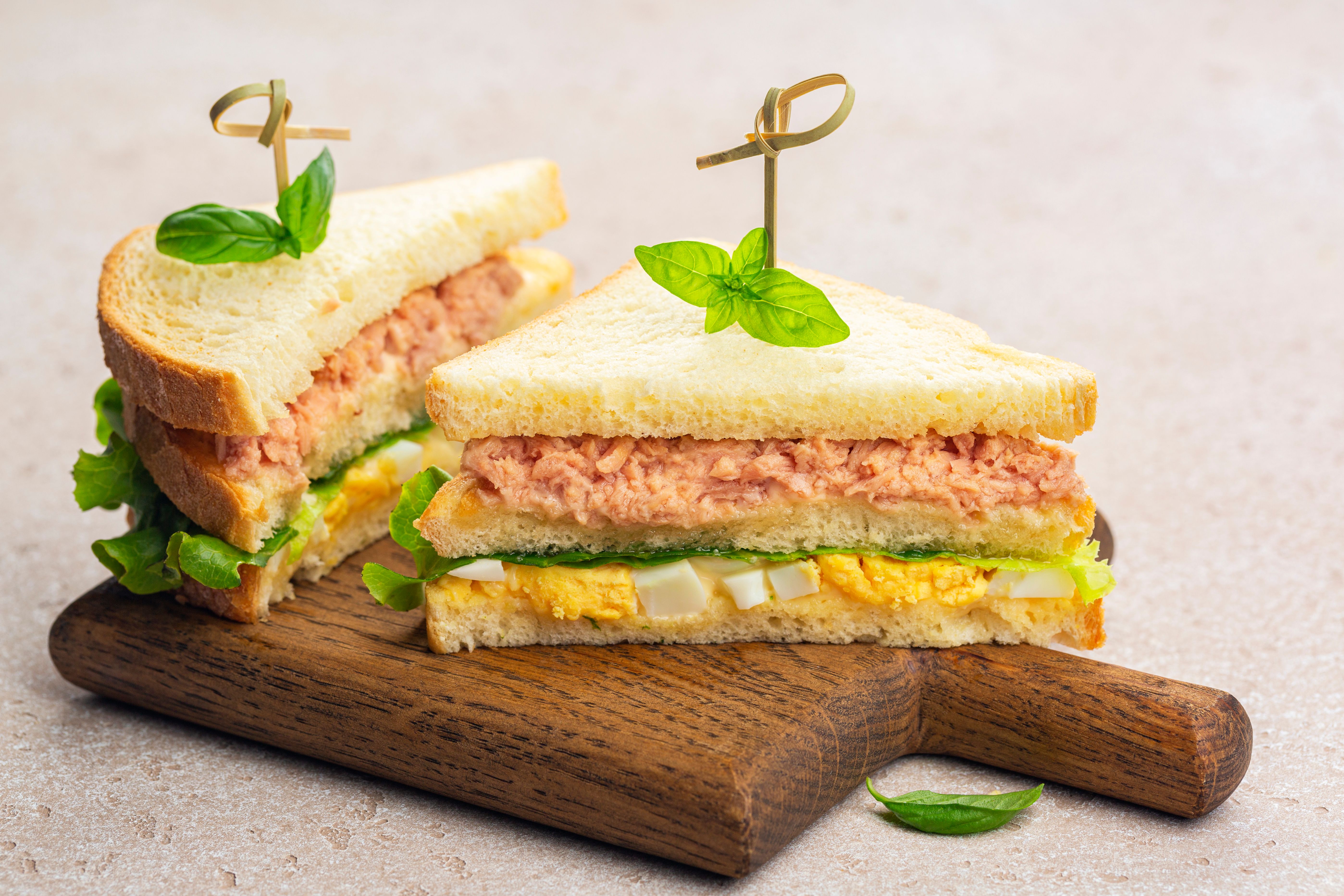 Two Tuna sandwich with boiled egg, mayonnaise, lettuce on a wooden board.
