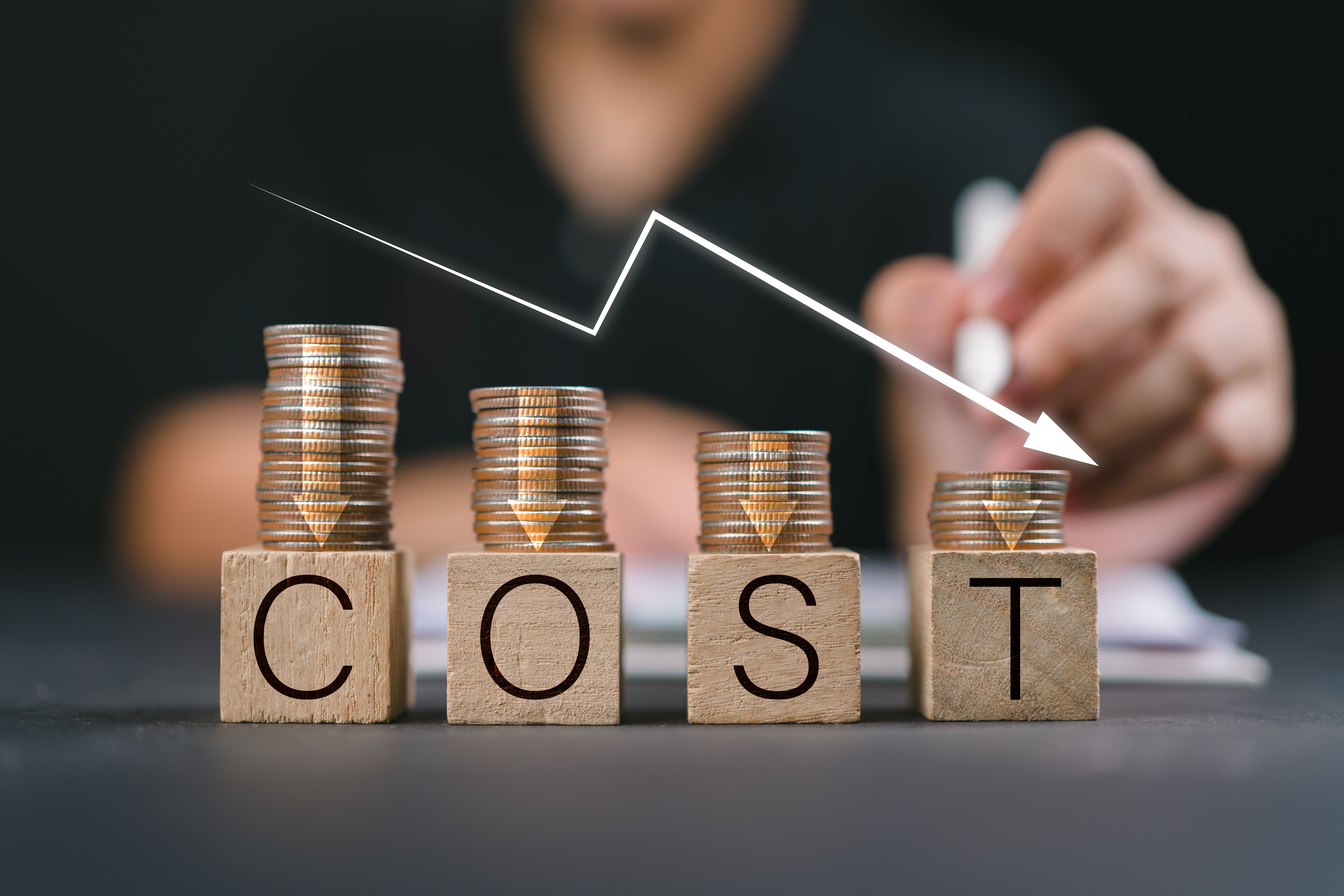 Cost reduction concept. Cost wording on decreasing coins stacking with the down arrow. Businessman working on company cost saving. Cost Management, Economy recession, low budget, Effective business,
