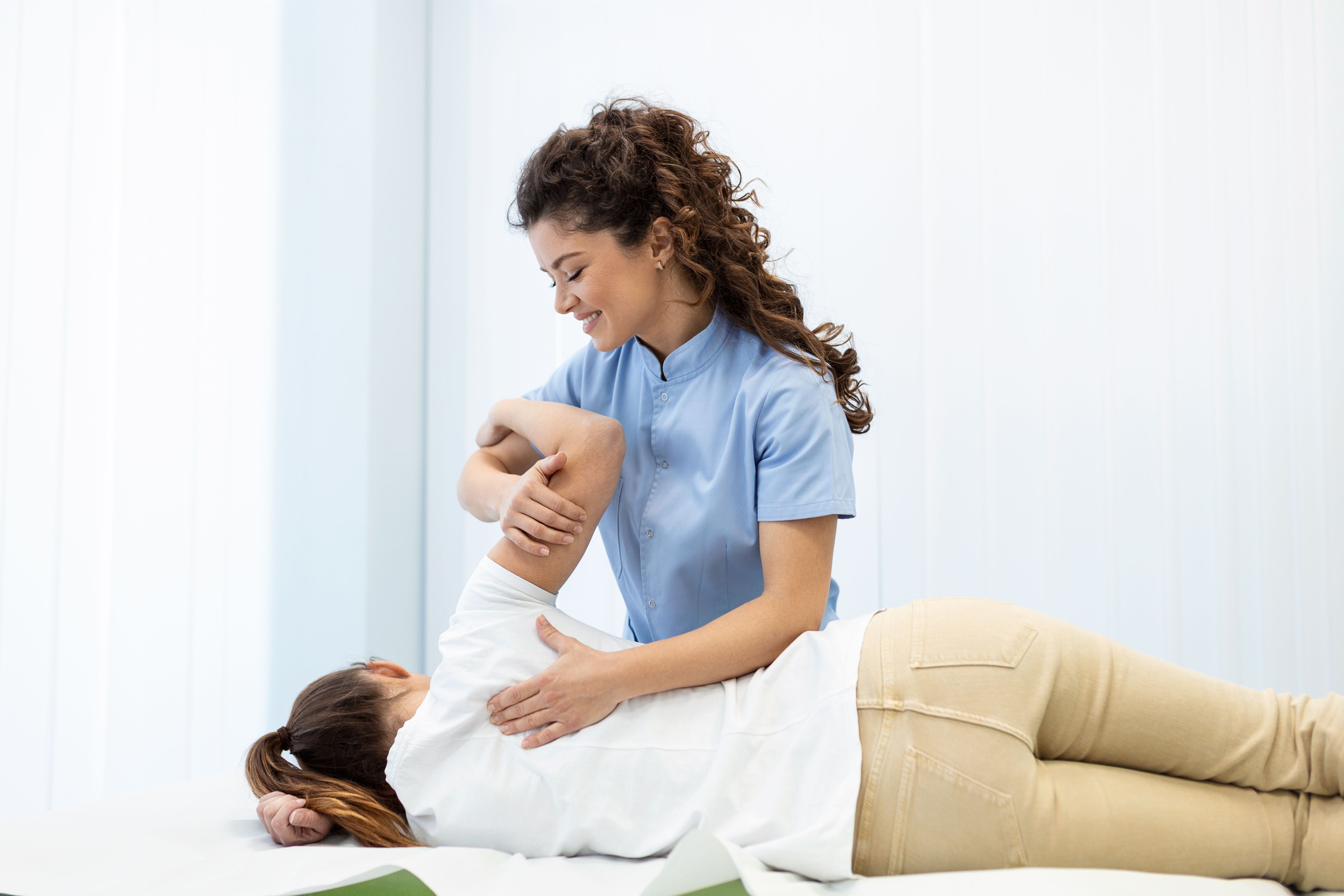 Physiotherapist treatment patient. Holding patient's hand, shoulder joint treatment. Physical Doctor consulting with patient About Shoulder muscule pain problems Physical therapy diagnosing concept Physiotherapist treatment patient. Holding patient's hand, shoulder joint treatment. Physical Doctor consulting with patient About Shoulder muscule pain problems Physical therapy diagnosing concept