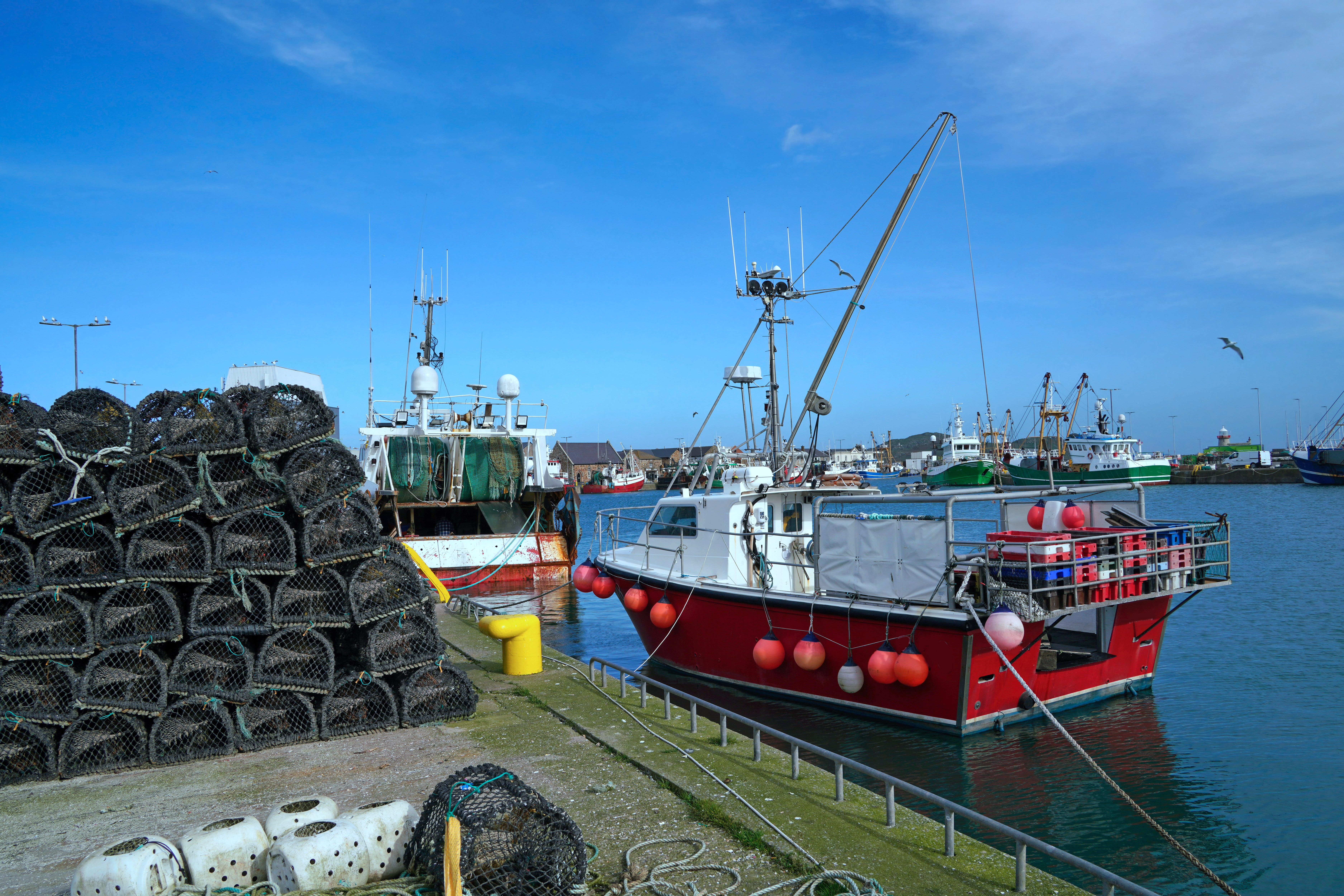 Fishing boats at dock beside a stack of lobster traps