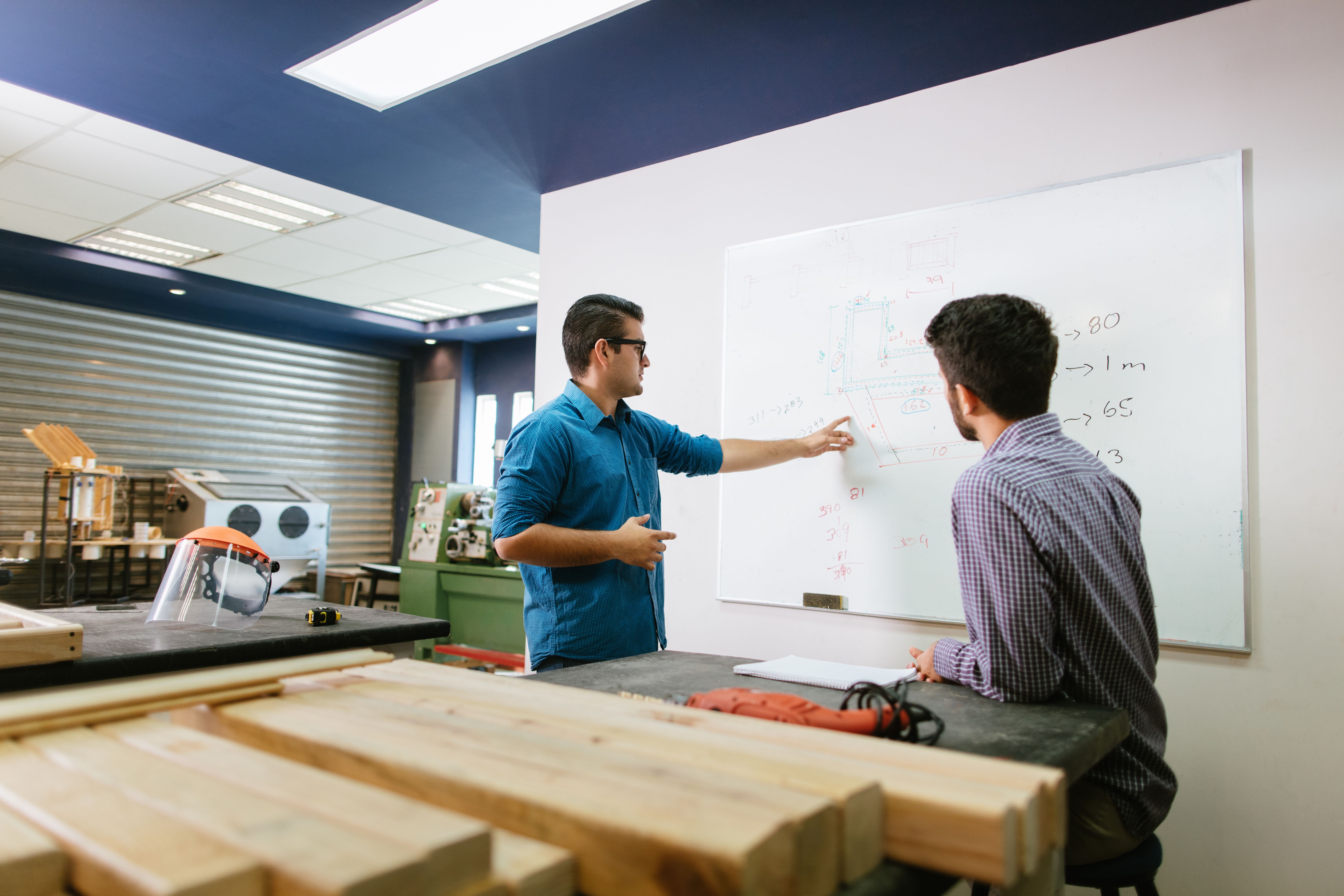 Latin engineers going over strategies in shop Latin engineers going over strategies in shop