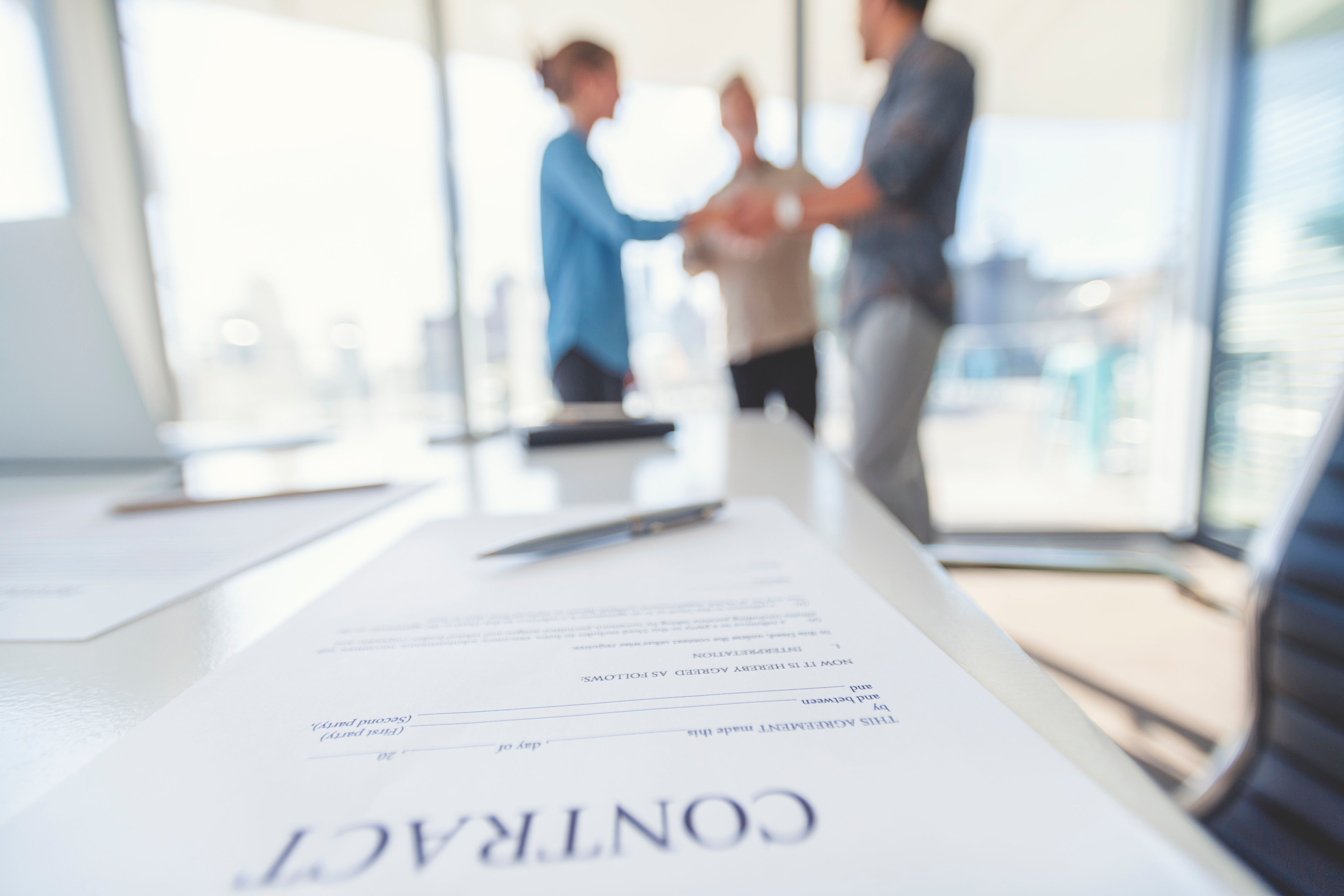 Business woman and business man shaking hands with a contract.