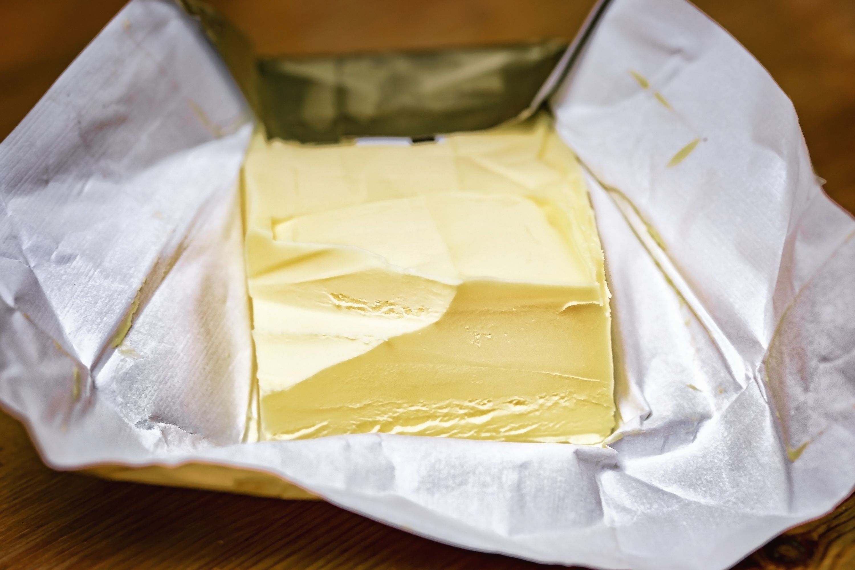 A piece of butter in golden paper on the table.