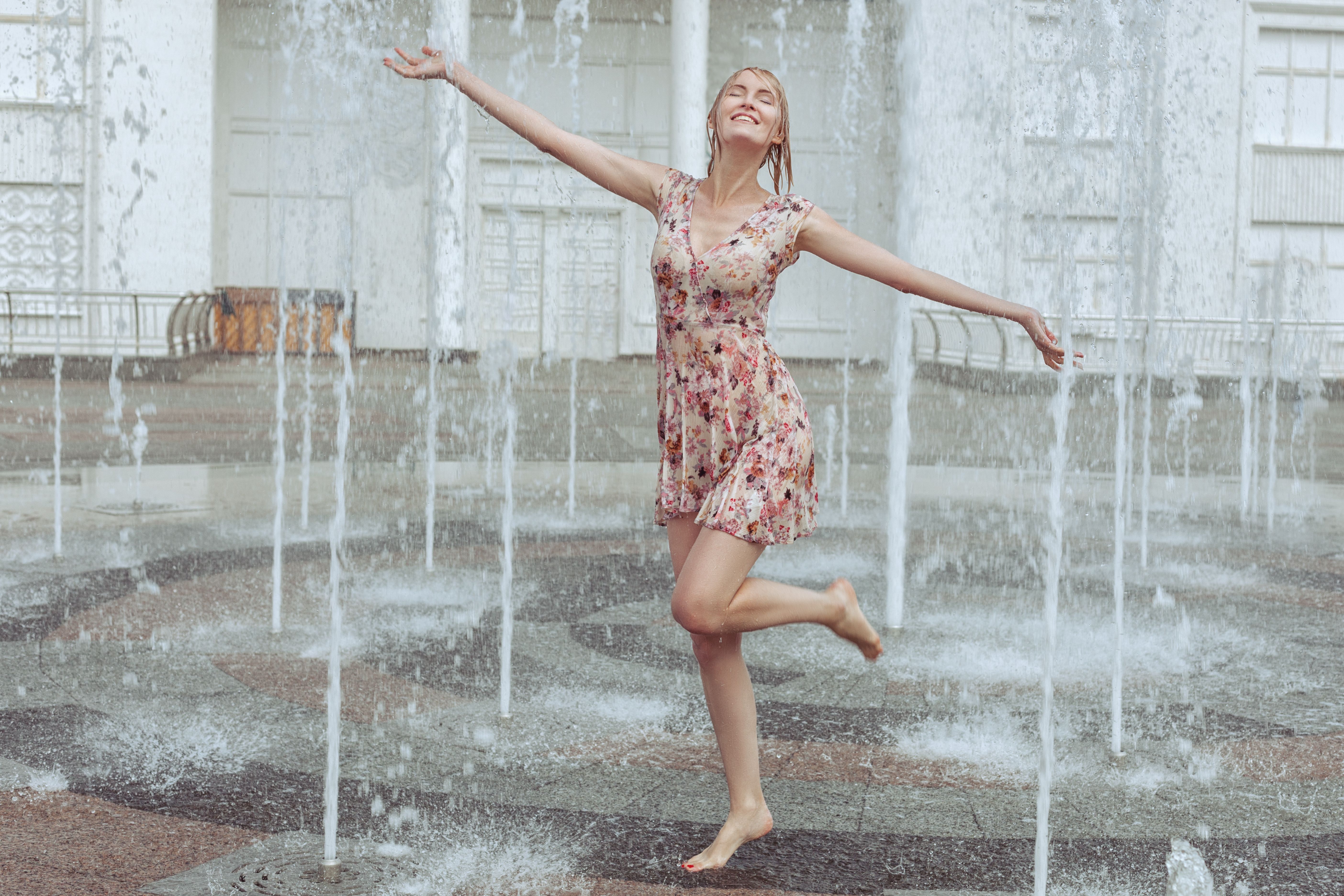 Happy woman frolics in a fountain.