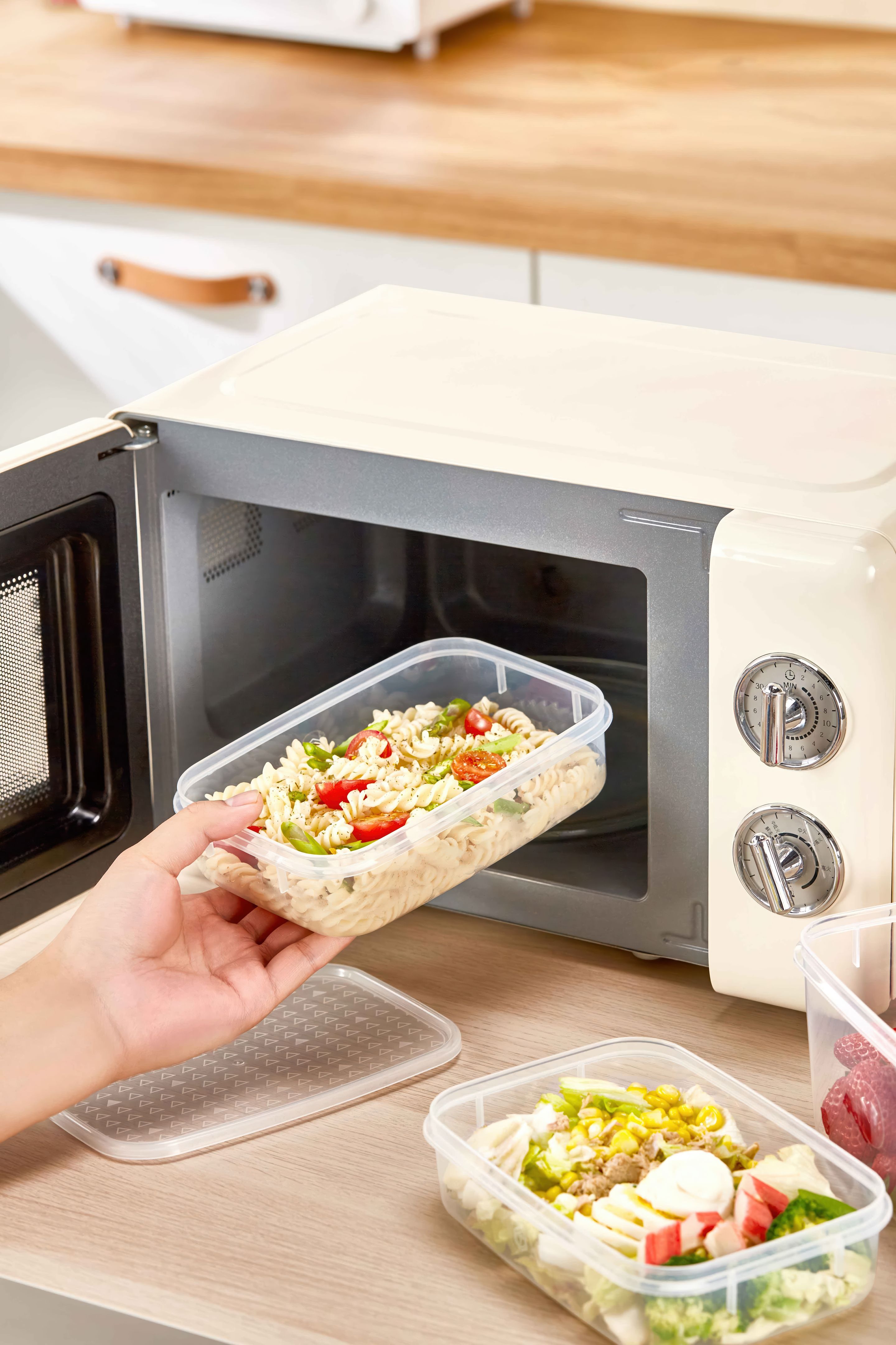 Heating Leftovers in Microwave Using Plastic Food Containers, Man taking out a healthy lunch from a toaster in the kitchen
