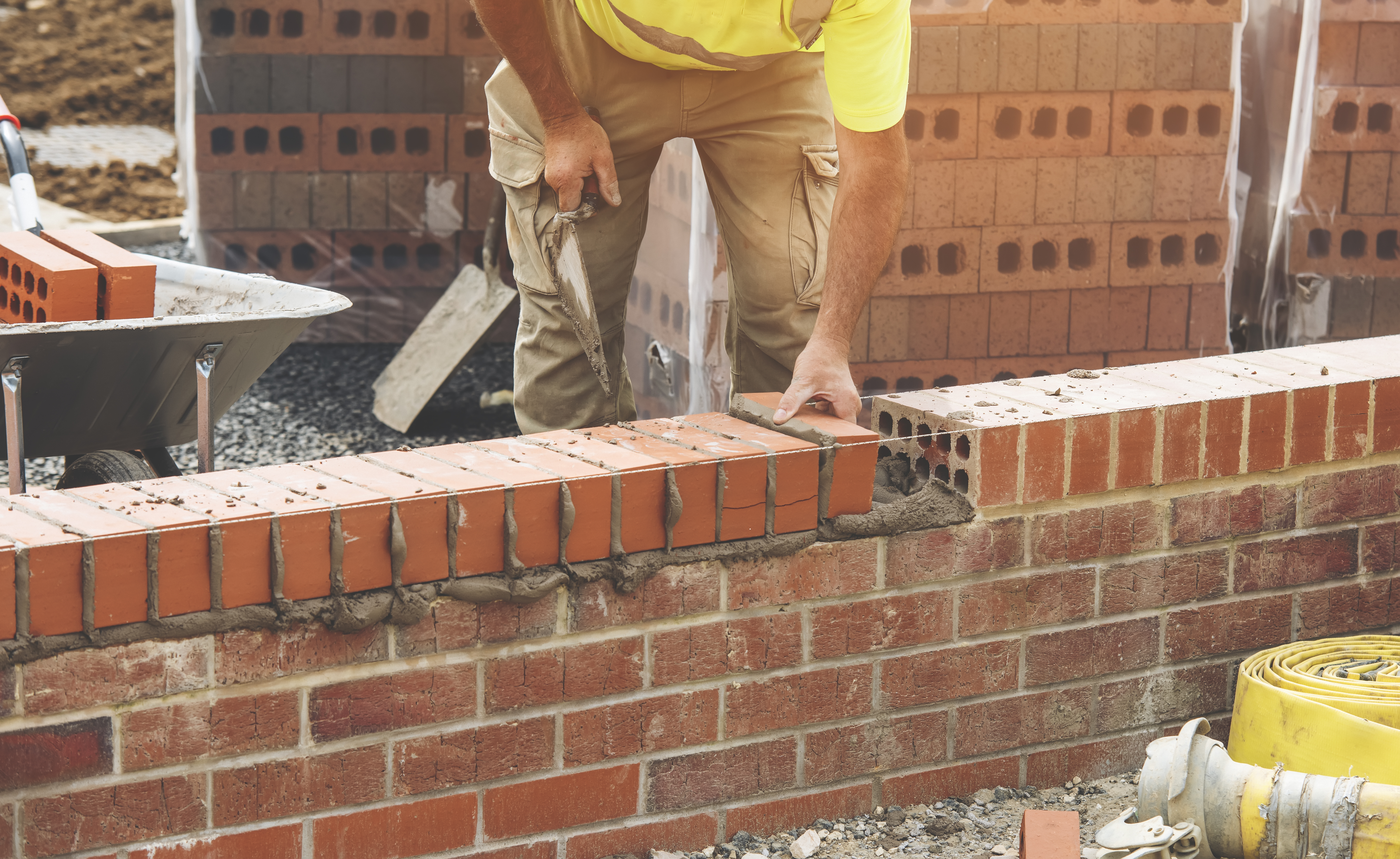 Industrial bricklayer laying bricks on cement mix on construction site