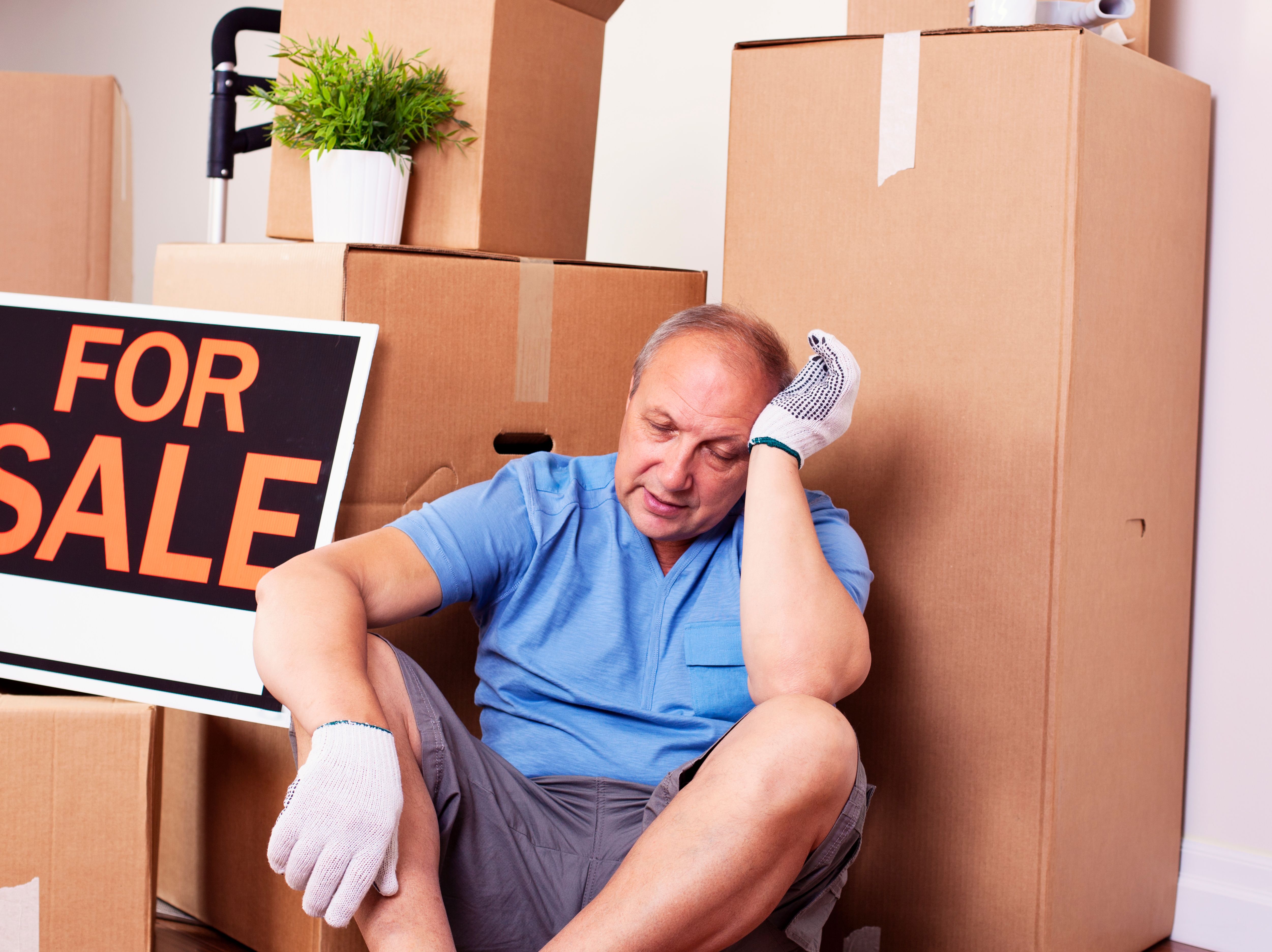 Tired mature man surrounded by boxes