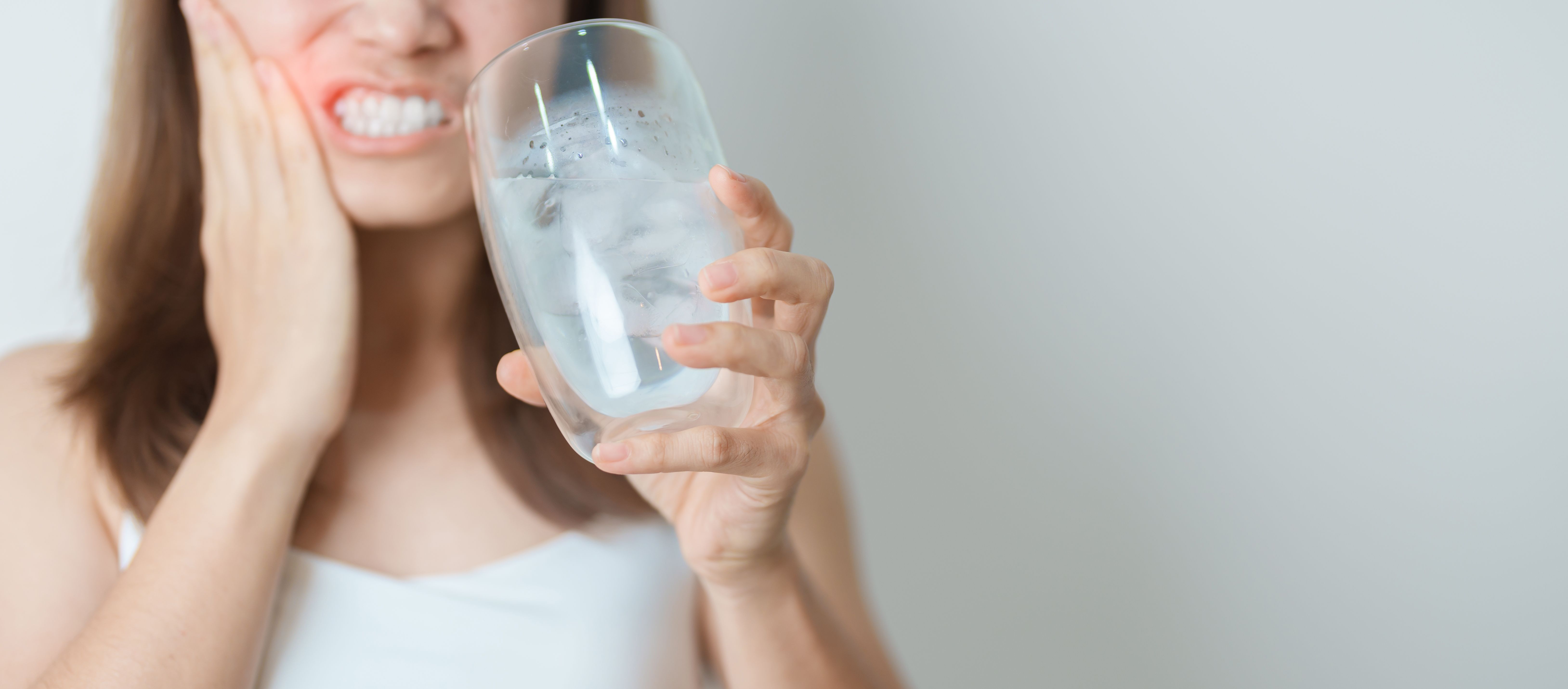 Teeth Sensitive to Cold concept. woman hold Ice Water glass and having toothache and pain after eat. Tooth Decay or Gum Disease, Grinding Teeth and Stress, Exposed Nerve Roots, Crack and Receding Gums