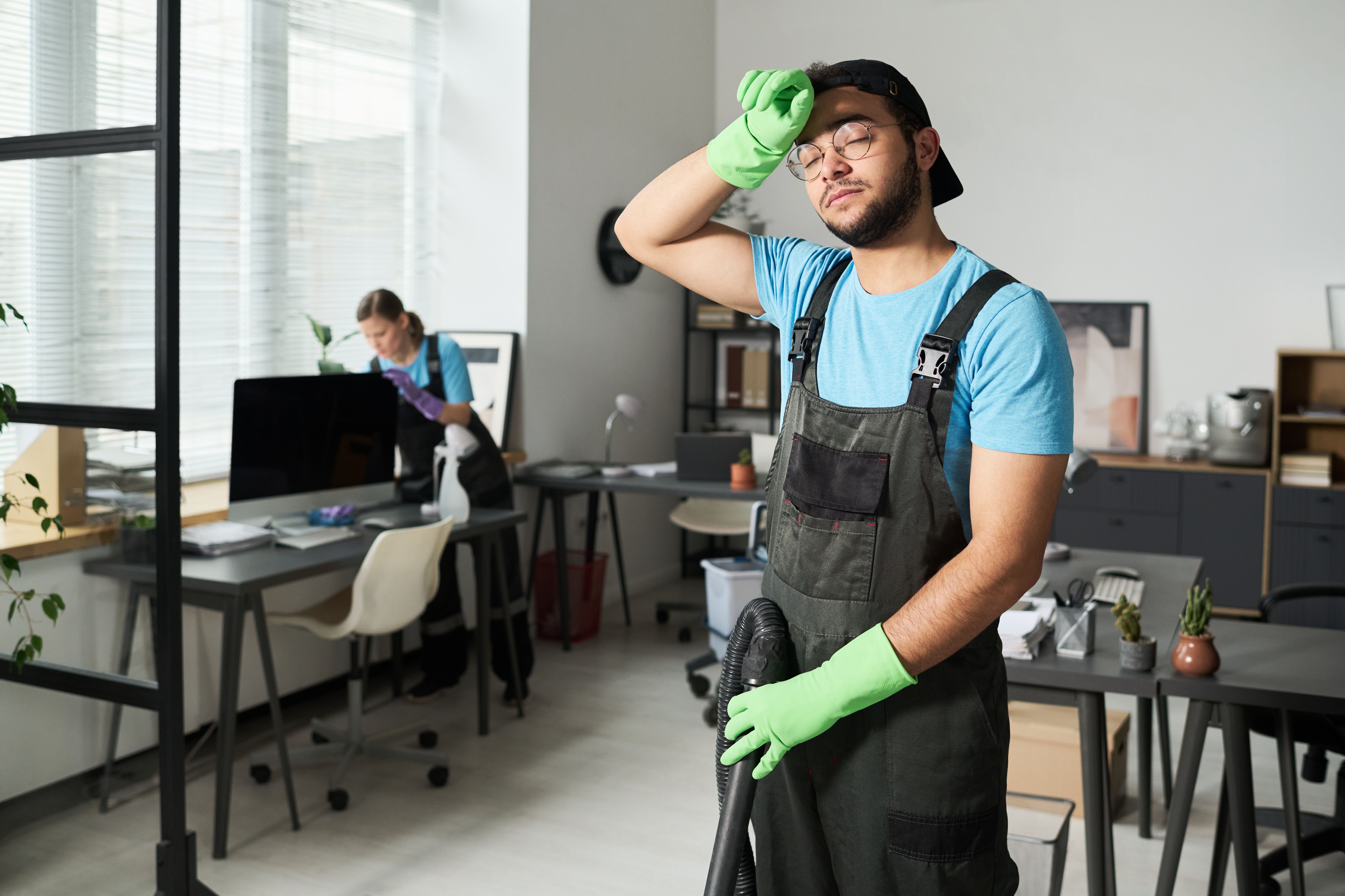 Tired Cleaner Doing Cleaning In Office