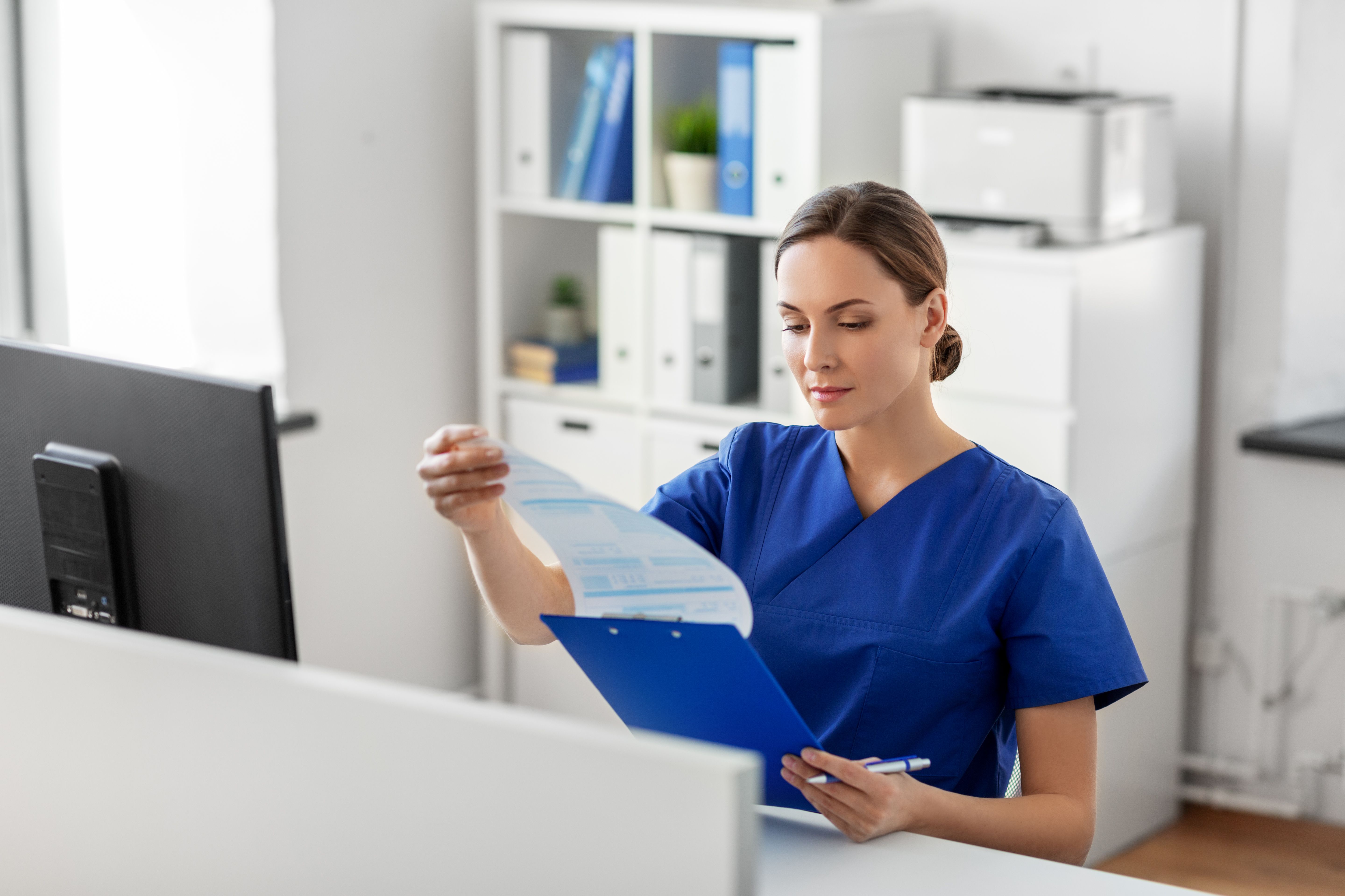 doctor or nurse with clipboard working at hospital