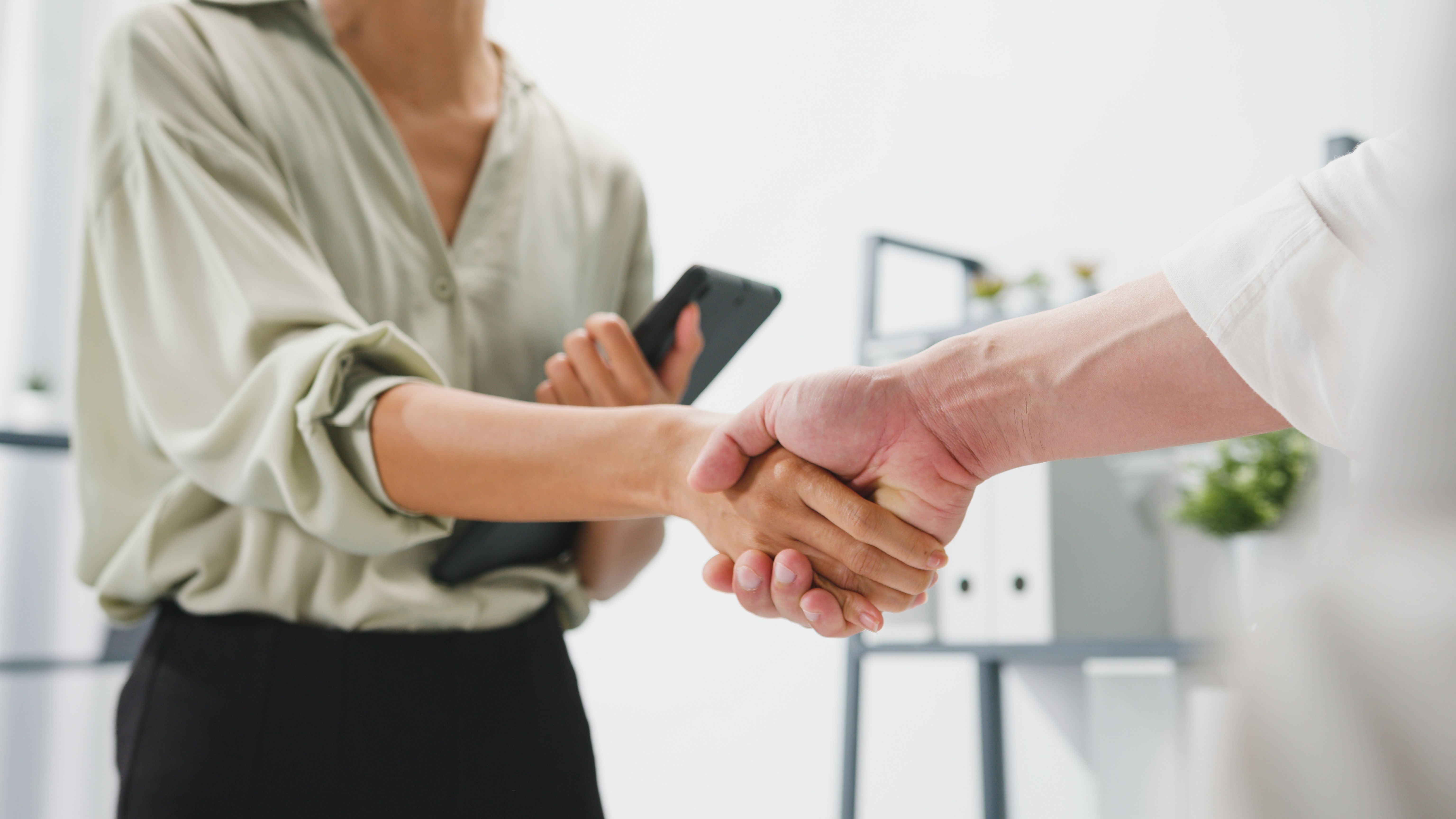 Multiracial group of young creative people in smart casual wear discussing business shaking hands together and smiling while standing in modern office. Multiracial group of young creative people in smart casual wear discussing business shaking hands together and smiling while standing in modern office.