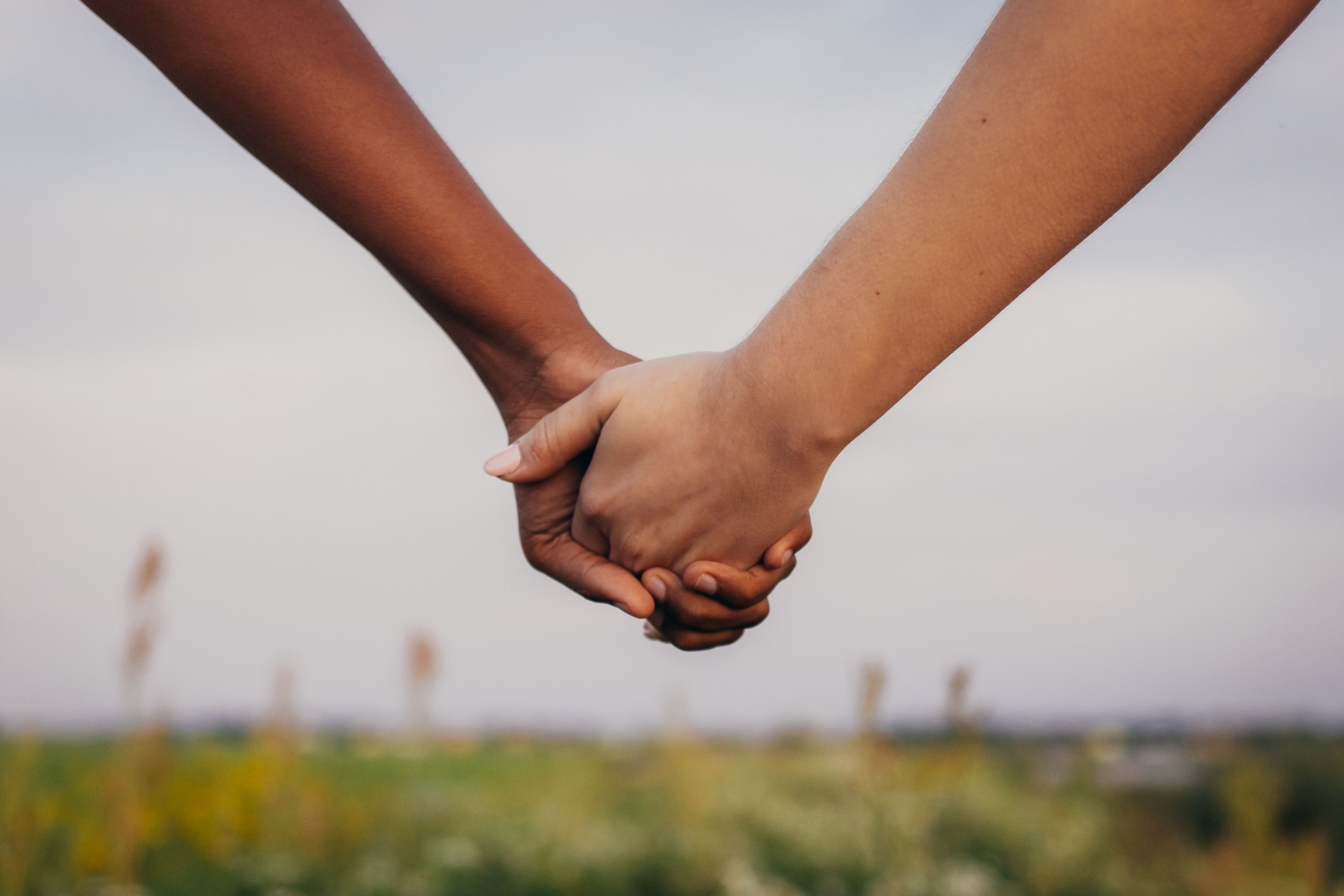 Close up of African and caucasian women holding hands on field