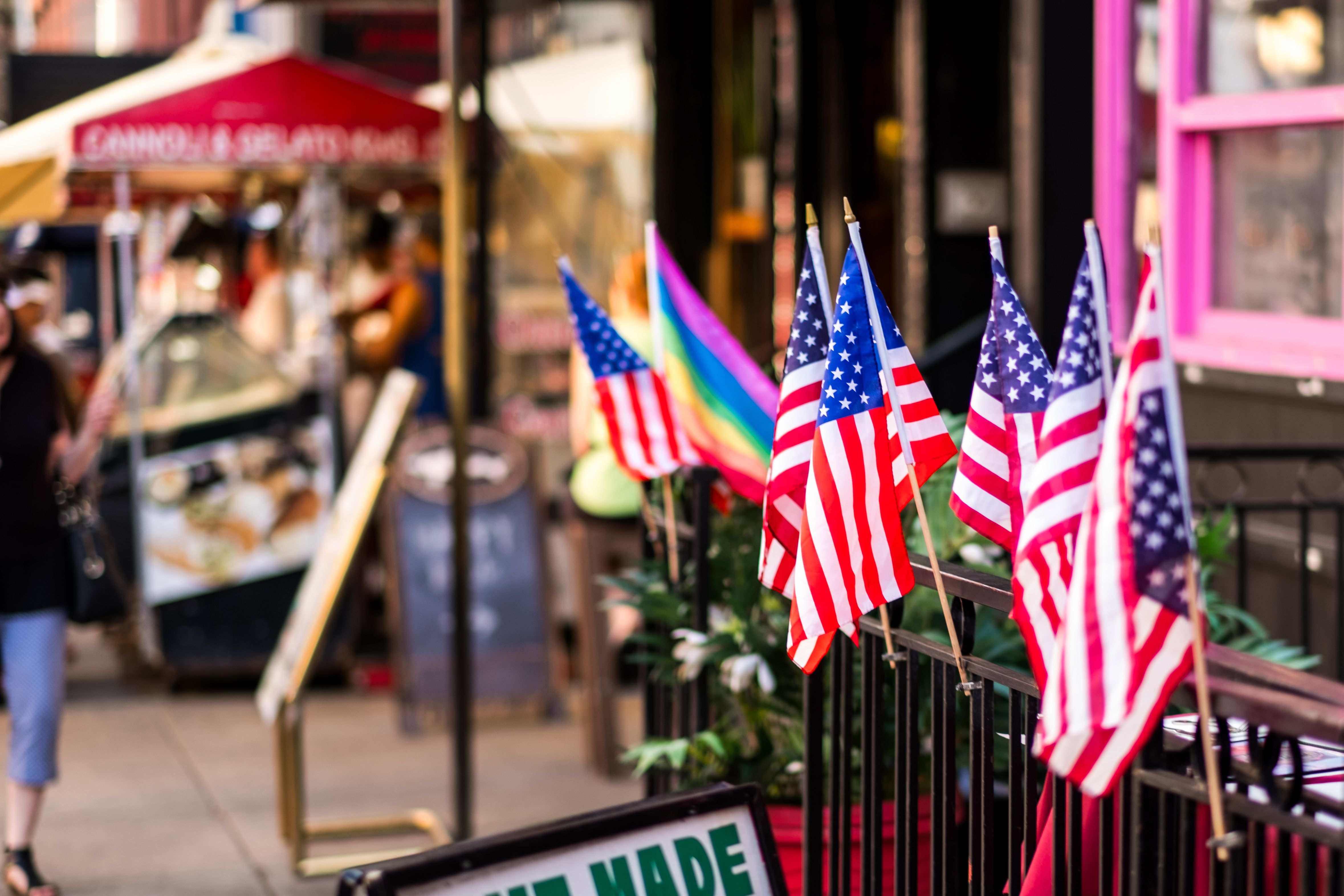 Vibrant Street Scene with American Flags and Rainbow Flag at Bustling City Market on a Sunny Day Celebrating Diversity and Patriotism
