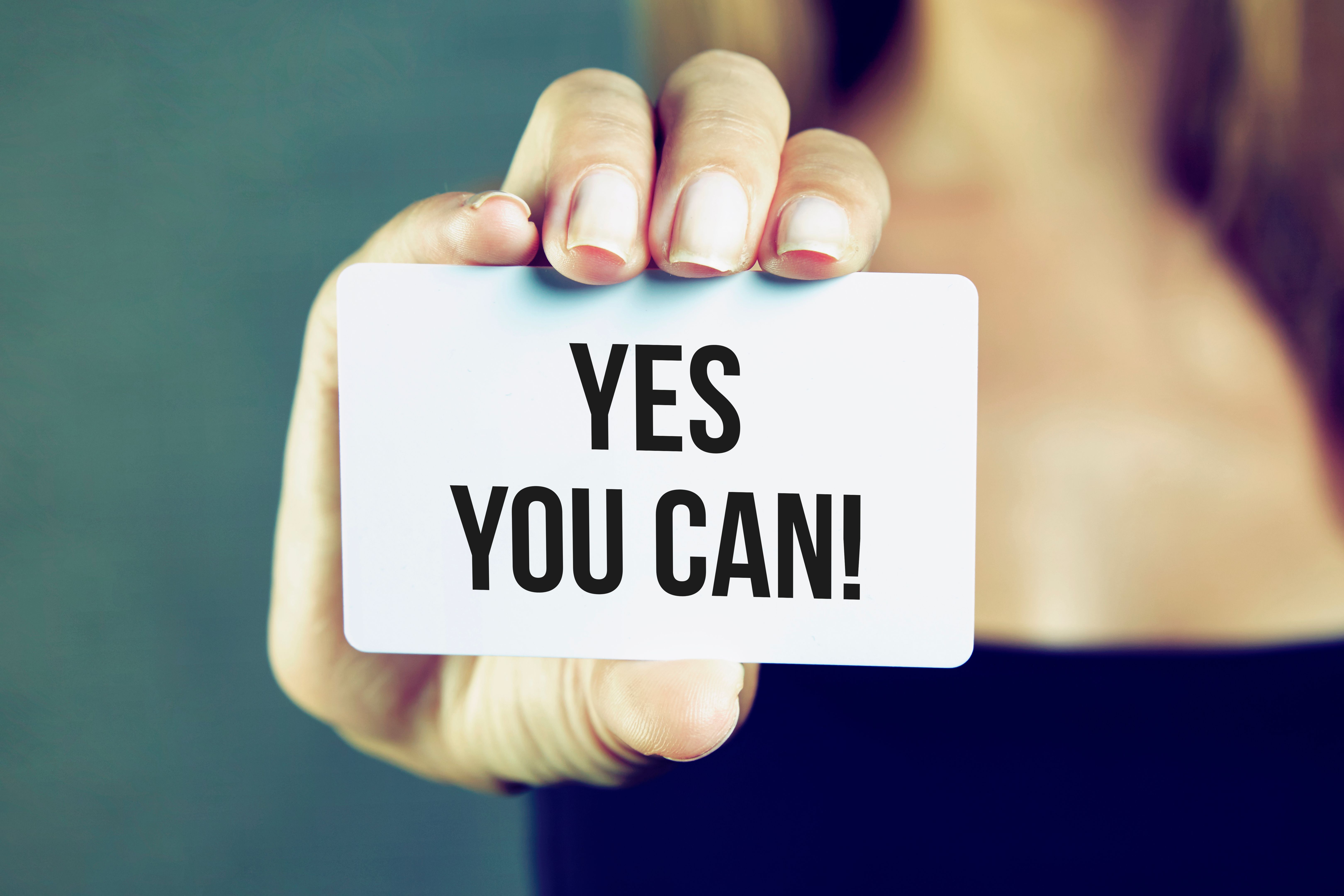 Young woman holding yes you can card