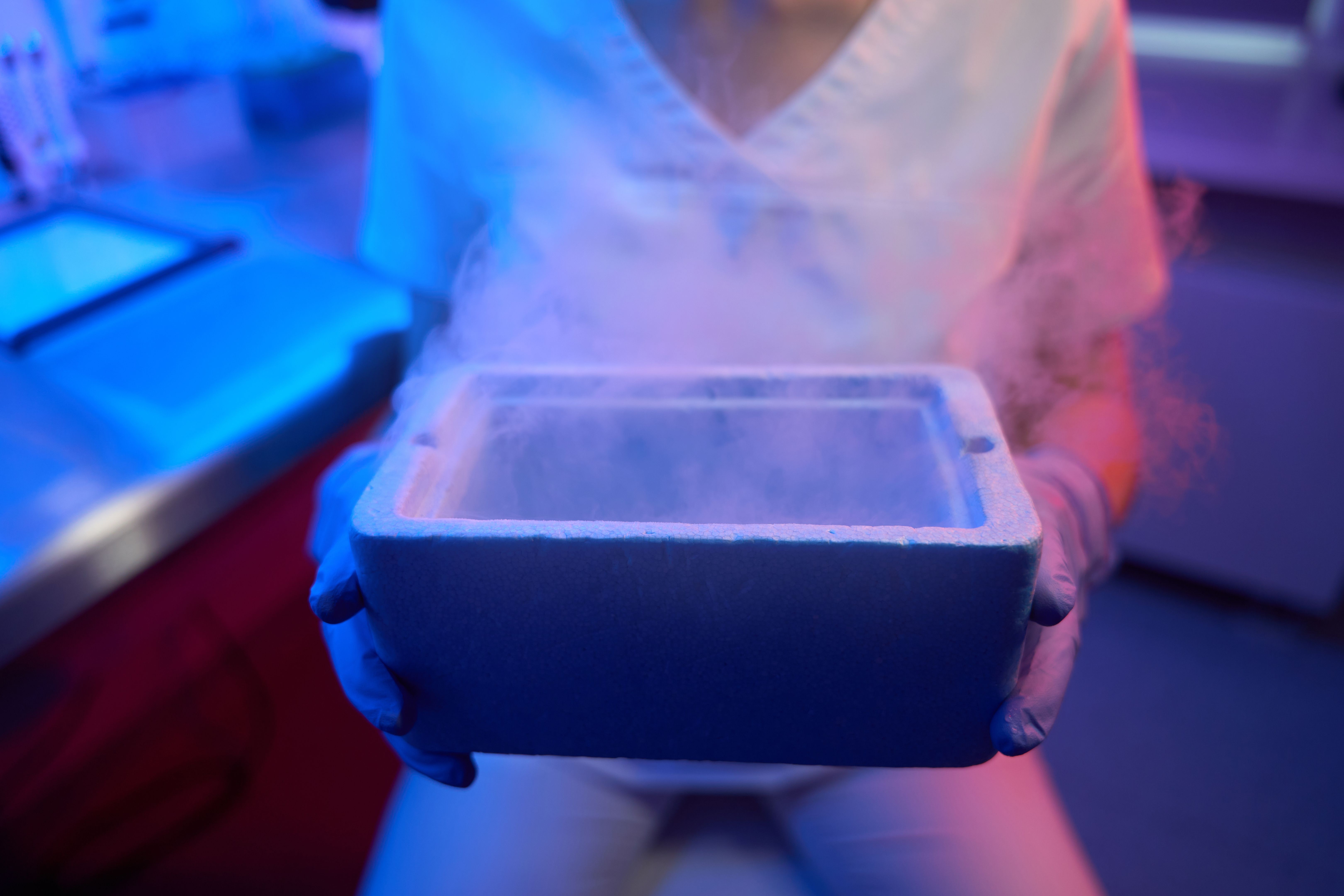 Female embryologist holding a tank for cryopreservation of biological material