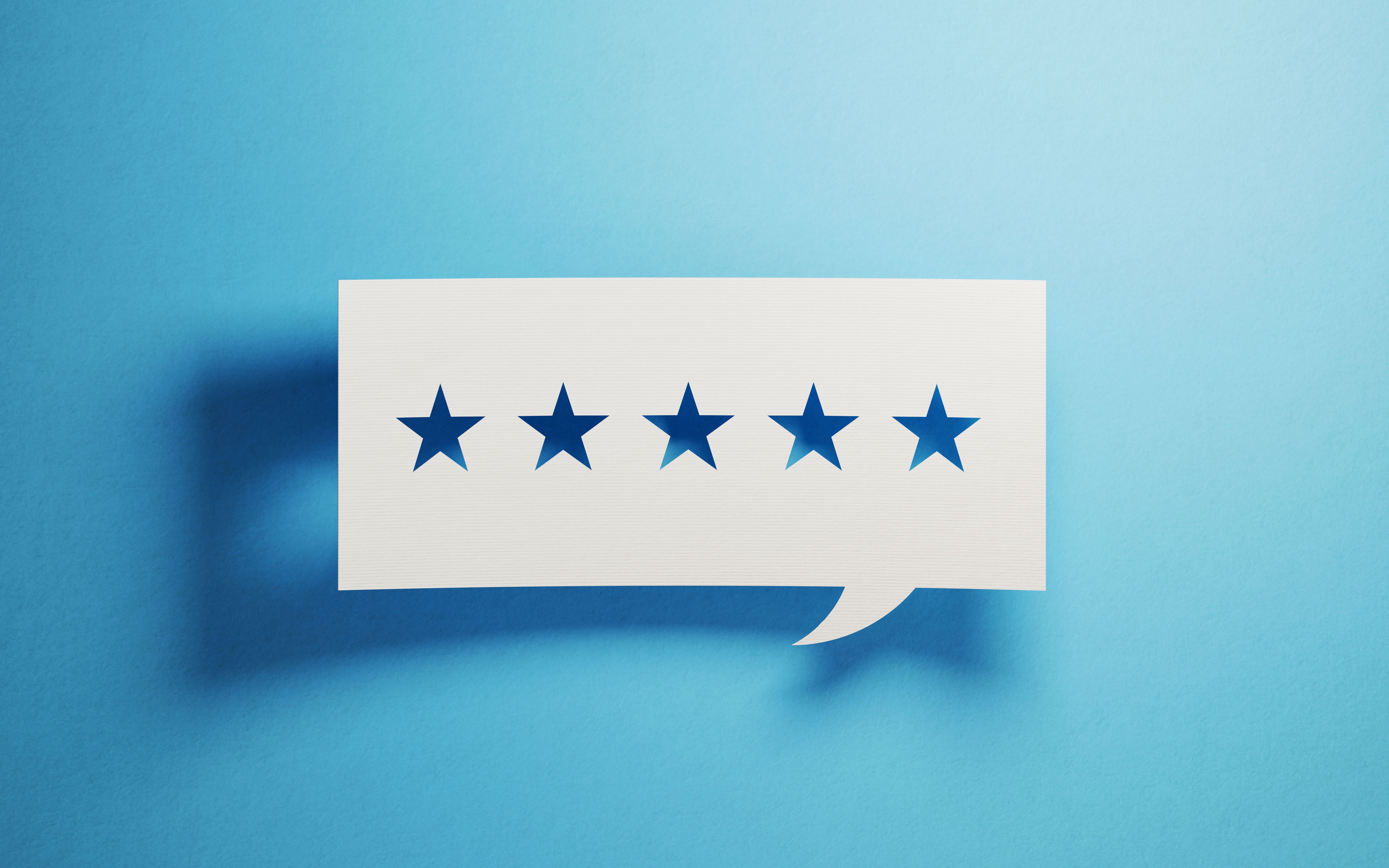 Feedback Concept - White Chat Bubble With Cut Out Star Shapes Over Blue Background Feedback Concept - White Chat Bubble With Cut Out Star Shapes Over Blue Background