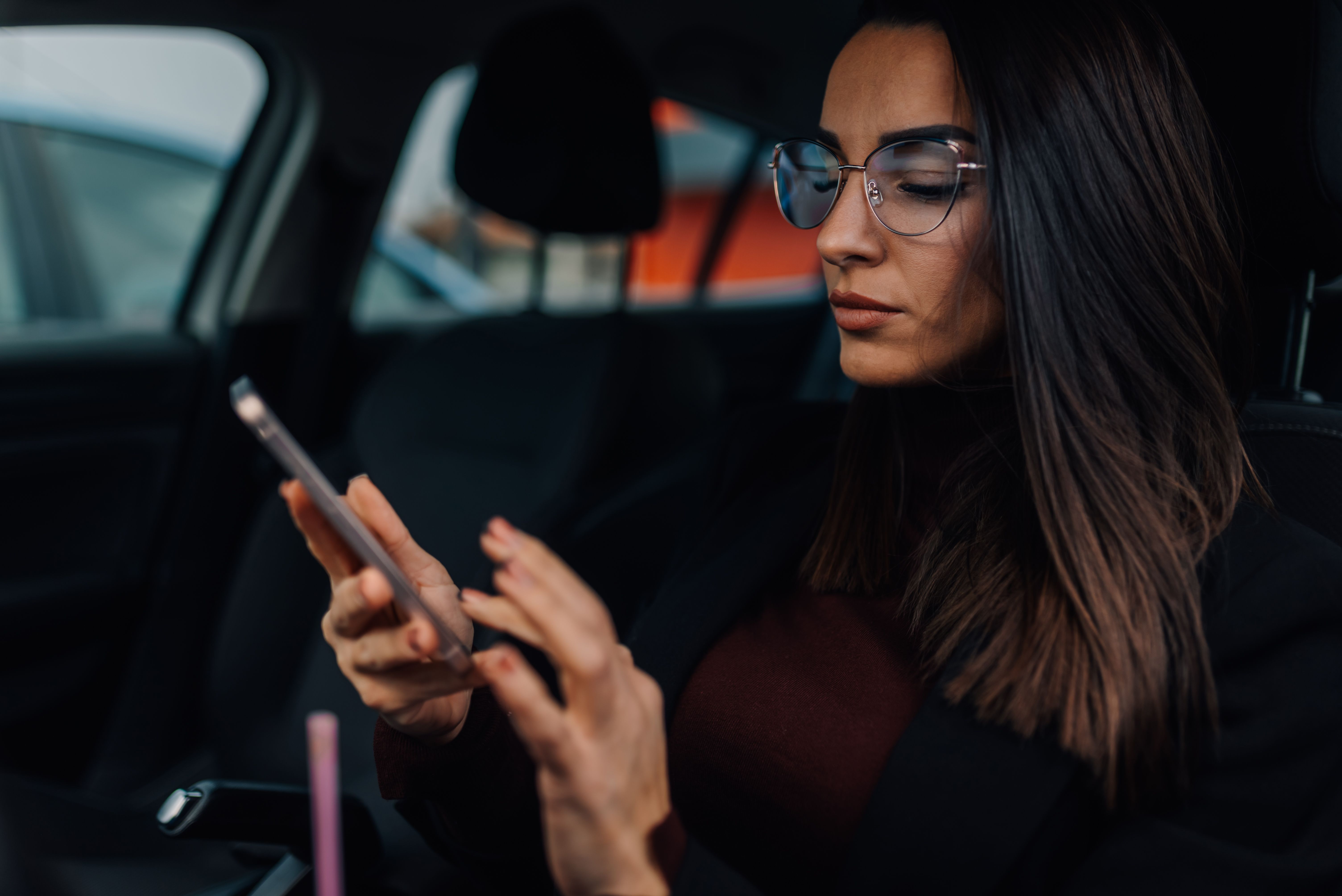 Businesswoman using smartphone while sitting in car, Belgrade Airport transfer