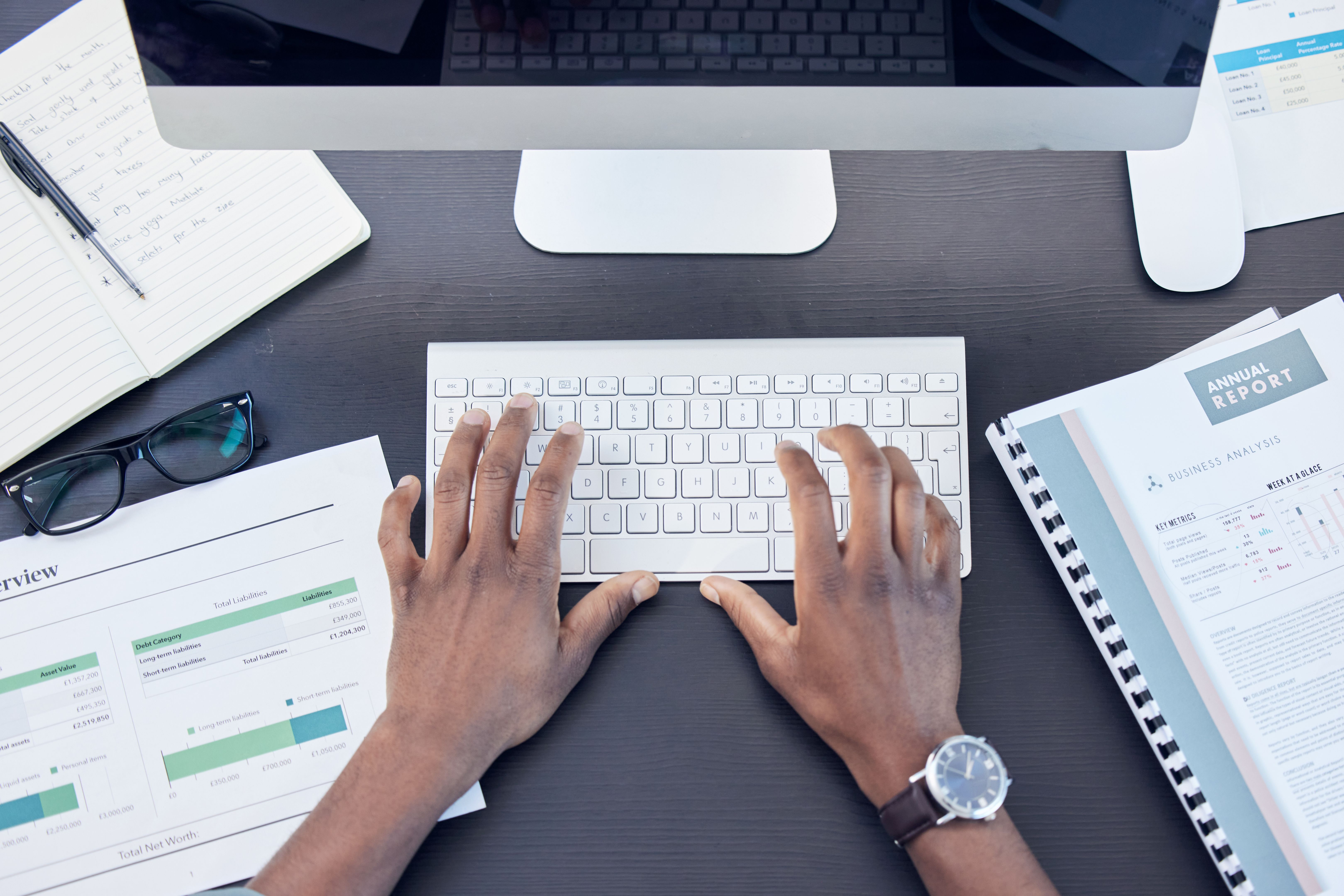 High angle shot of an unrecognizable businessman sitting alone in his office and using his computer High angle shot of an unrecognizable businessman sitting alone in his office and using his computer