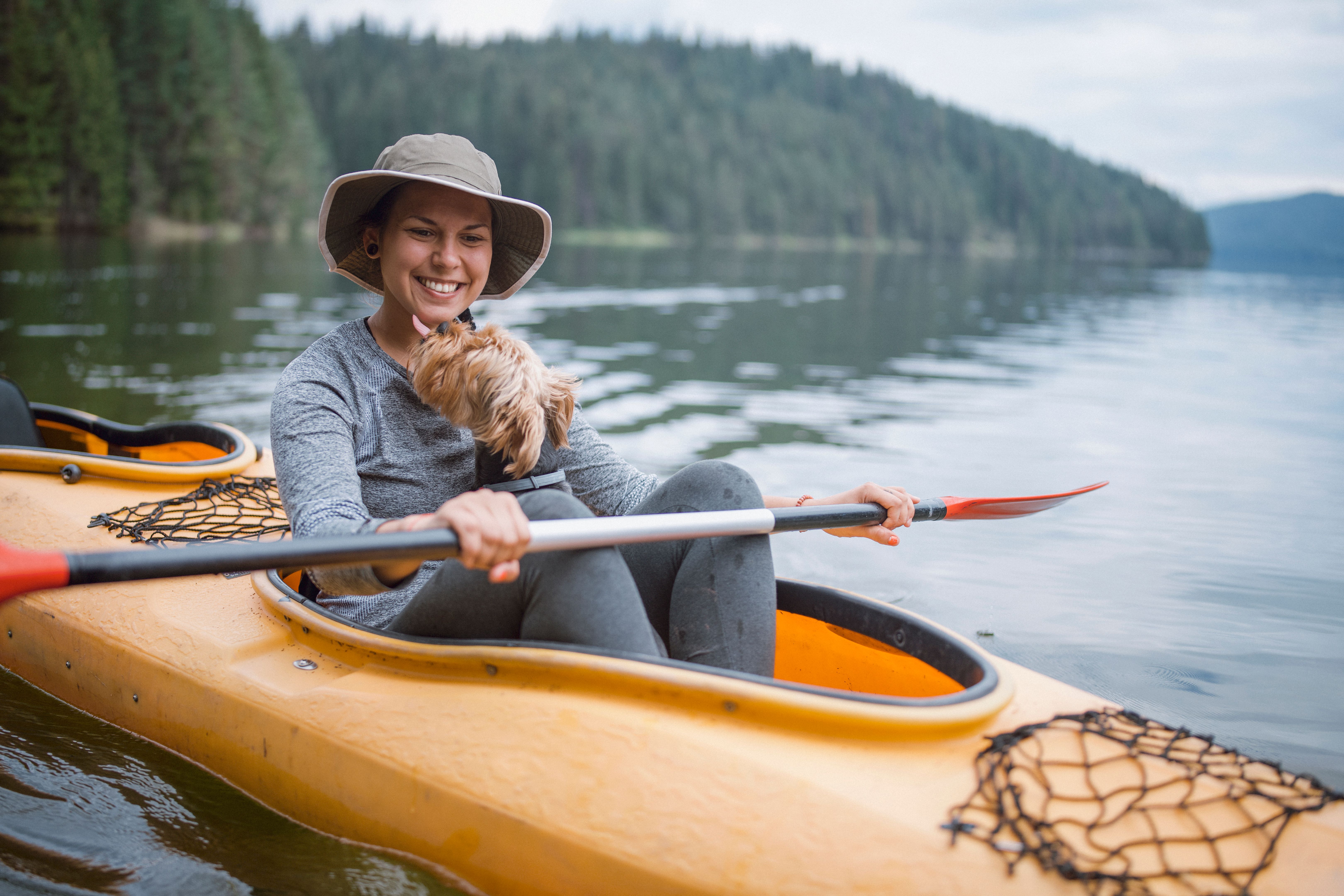 Young Woman Is Kayaking At Lake With Her Yorkshire Terrier Dog
