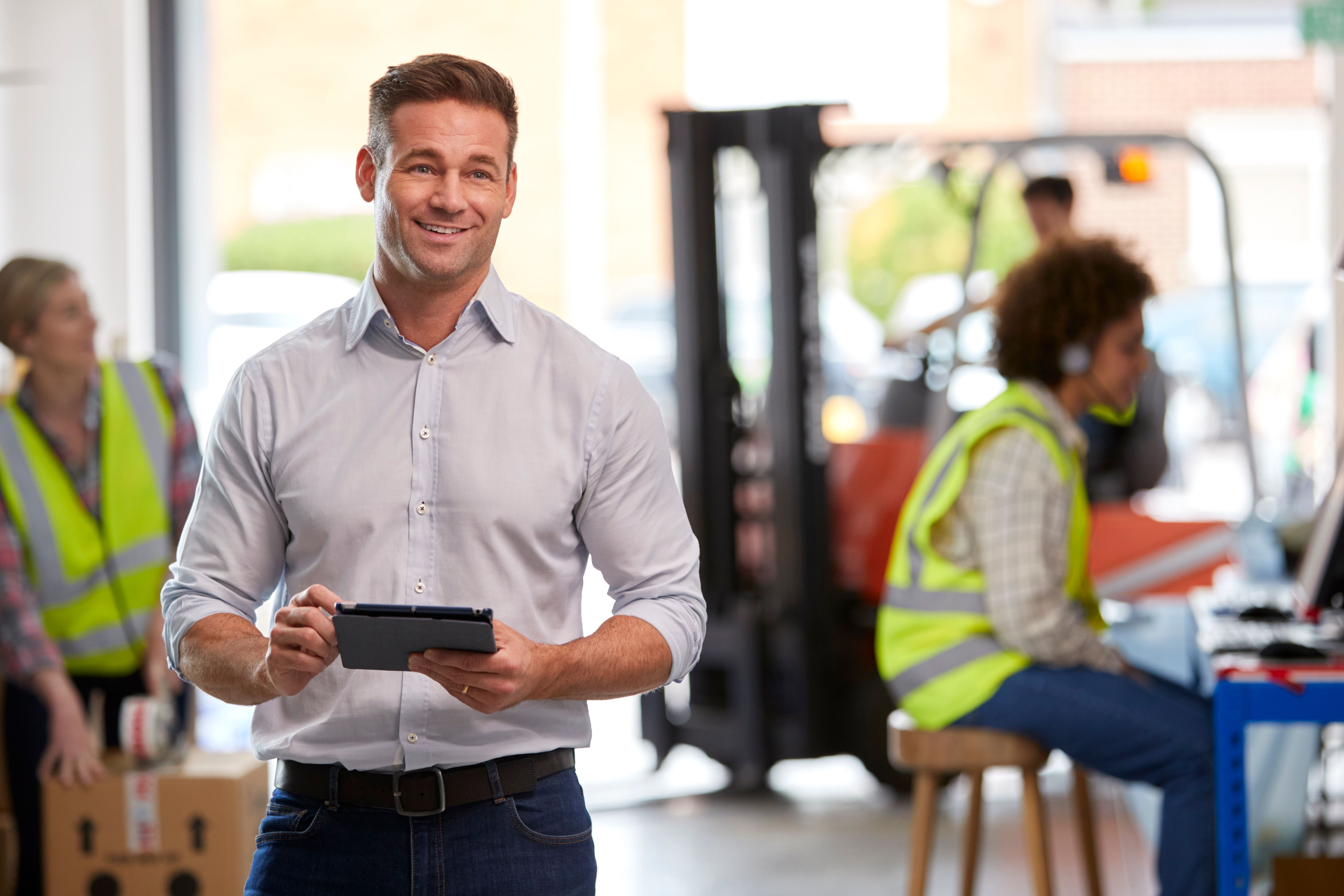 Male Manager In Logistics Distribution Warehouse Using Digital Tablet