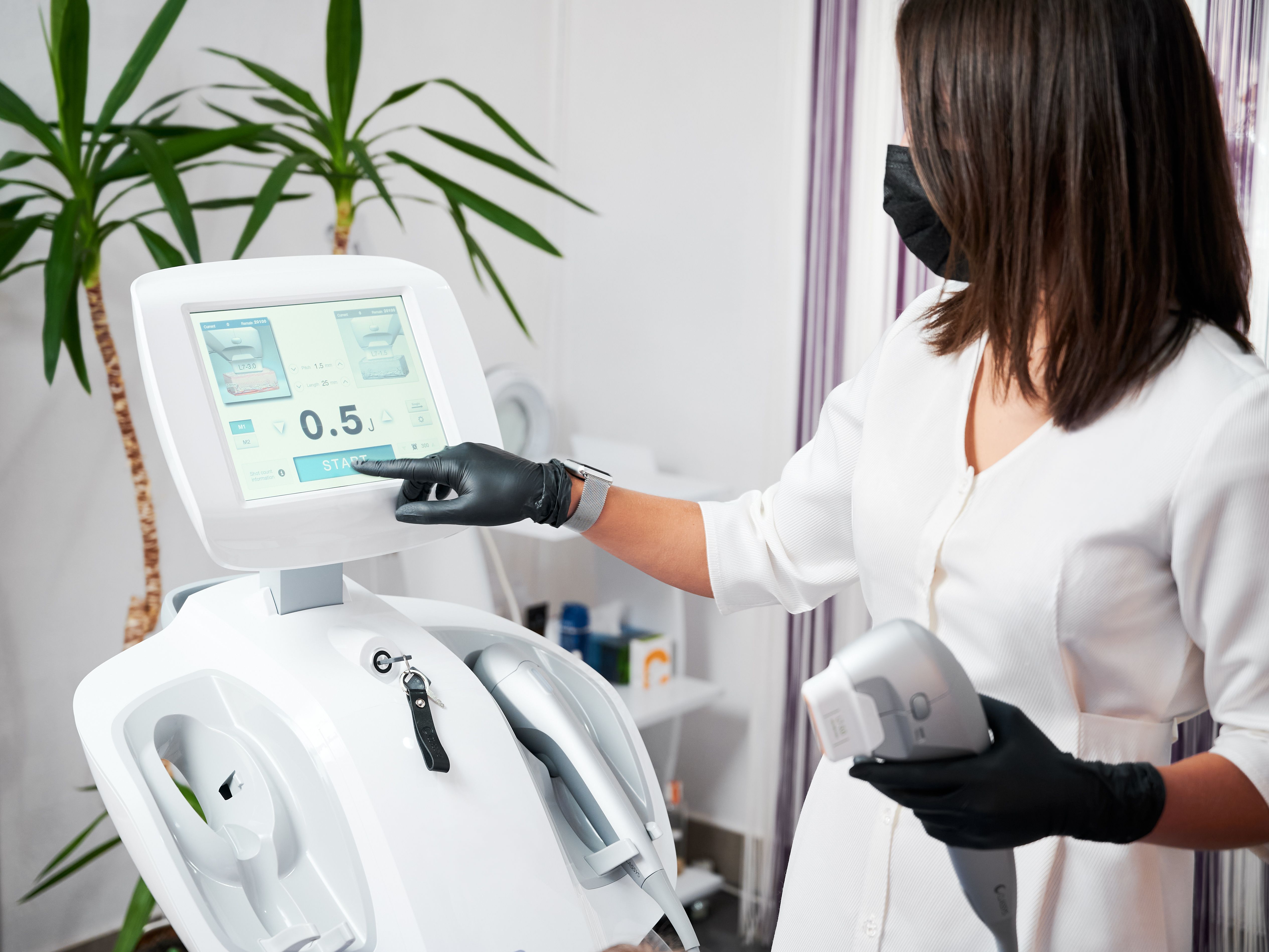 Female cosmetologist using ultrasound SMAS lifting machine.