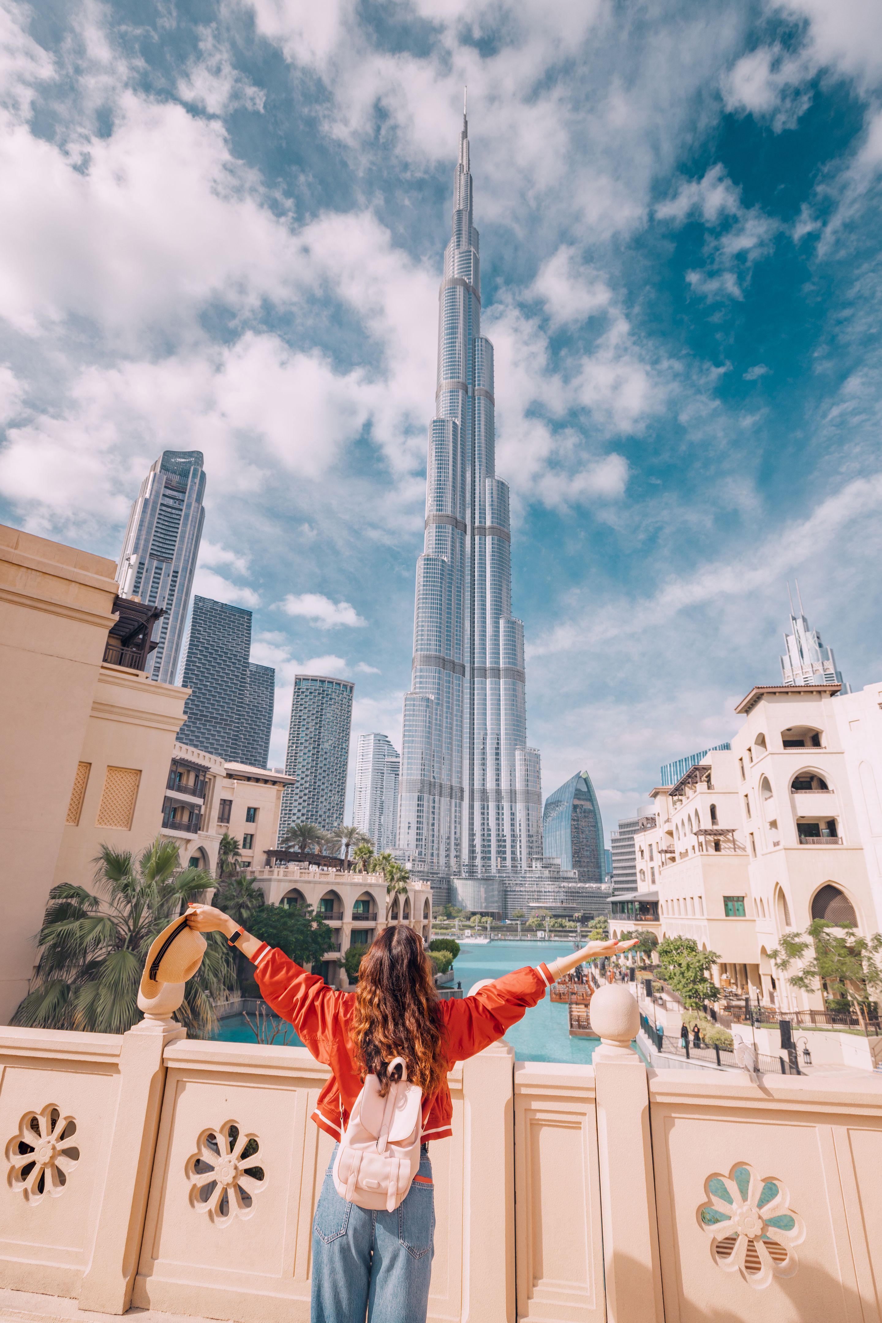 Happy girl arms are outstretched, as she embracing the incredible view before her with unreal Burj Khalifa tower in Dubai, UAE