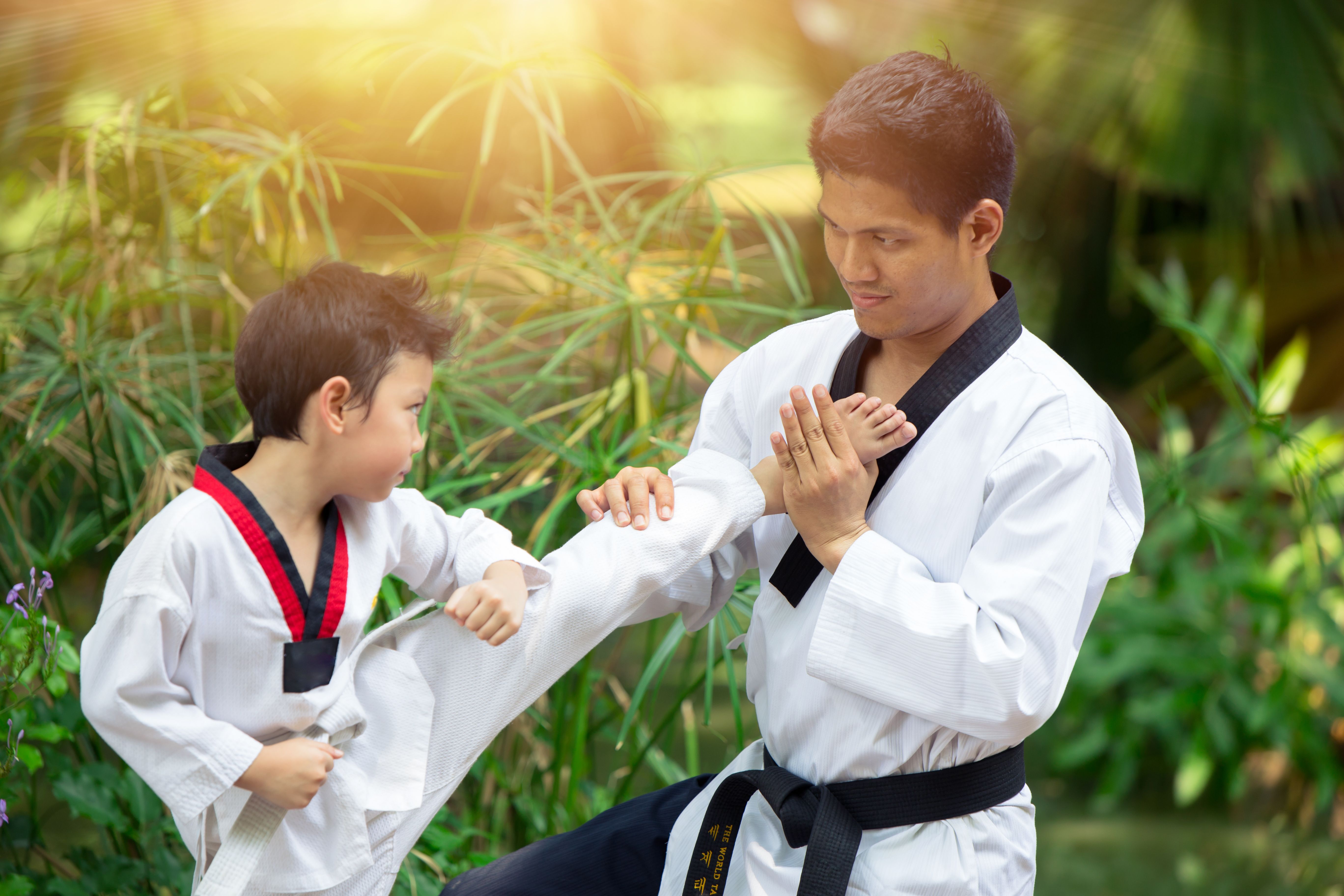 Boy and Dad enjoy healthy sport Taekwondo together outdoor for train fighter kick. Boy and Dad enjoy healthy sport Taekwondo together outdoor for train fighter kick.