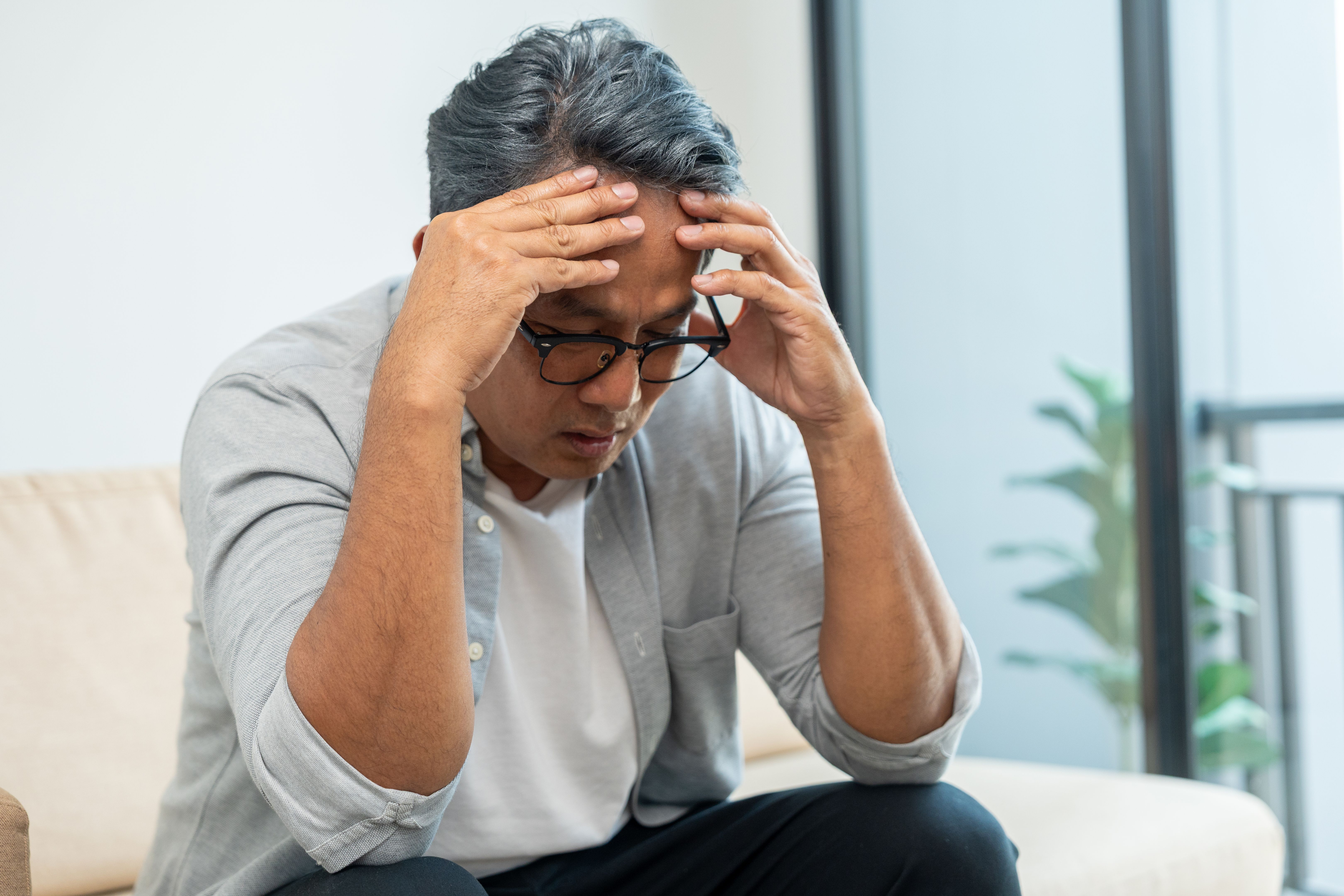 Asian mature old man sitting headache tired on sofa at home. Portrait of serious depression sadness senior asian man. Mature People Depressed problem in life Asian mature old man sitting headache tired on sofa at home. Portrait of serious depression sadness senior asian man. Mature People Depressed problem in life