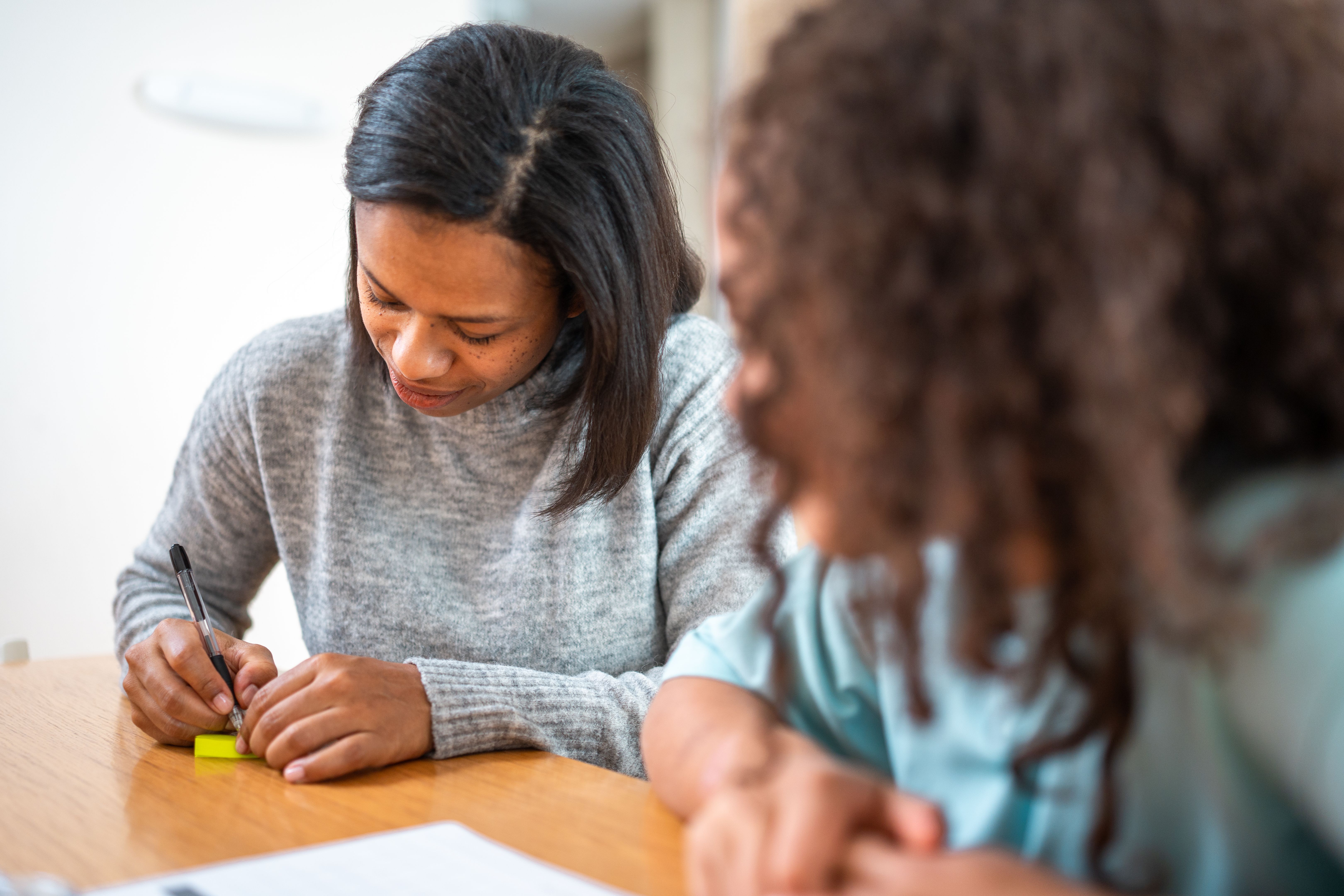 Mixed Race Mother and Daughter Collaborating on Homework with Sticky Notes at Home