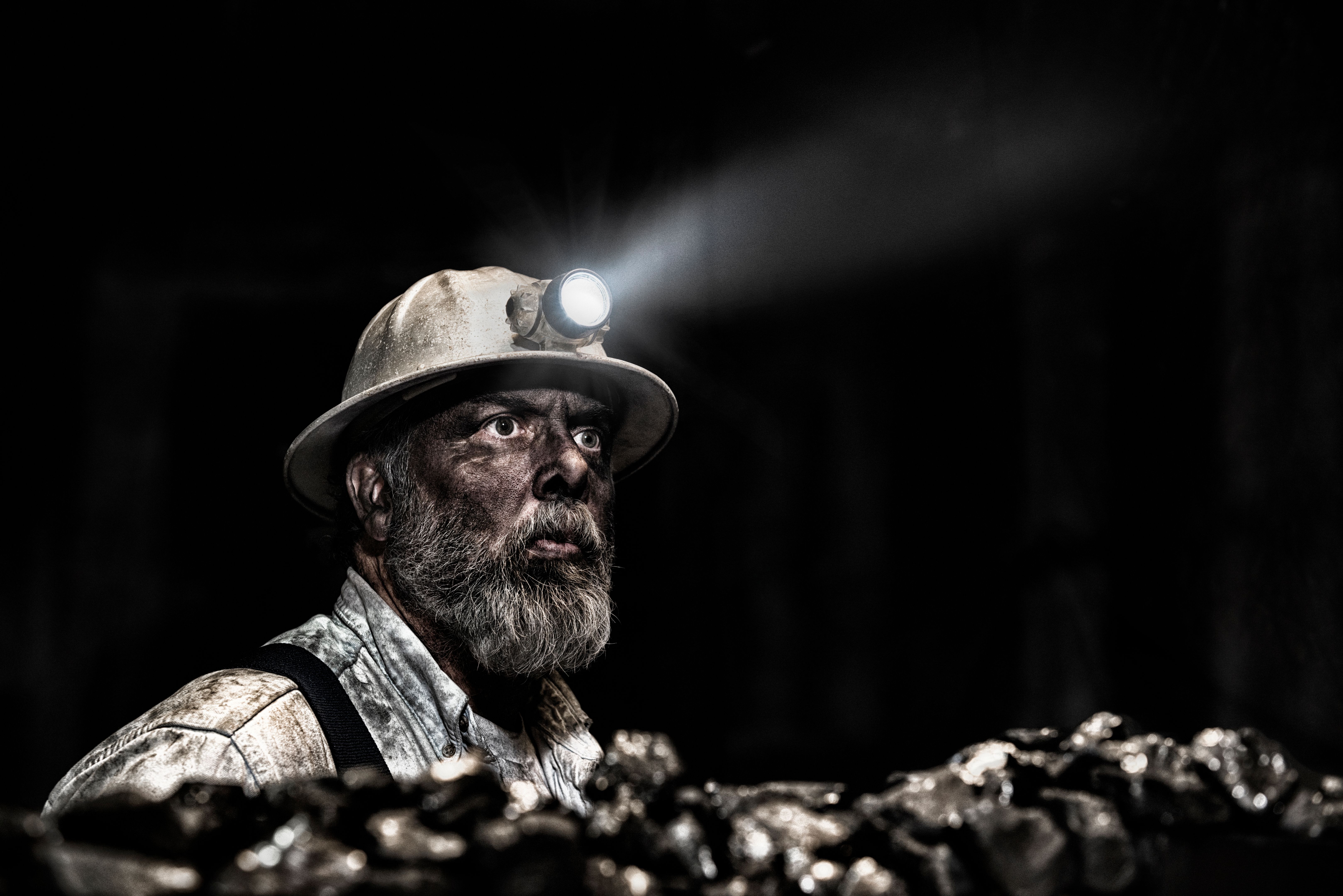Dirty coal miner wear hardhat with light in mine