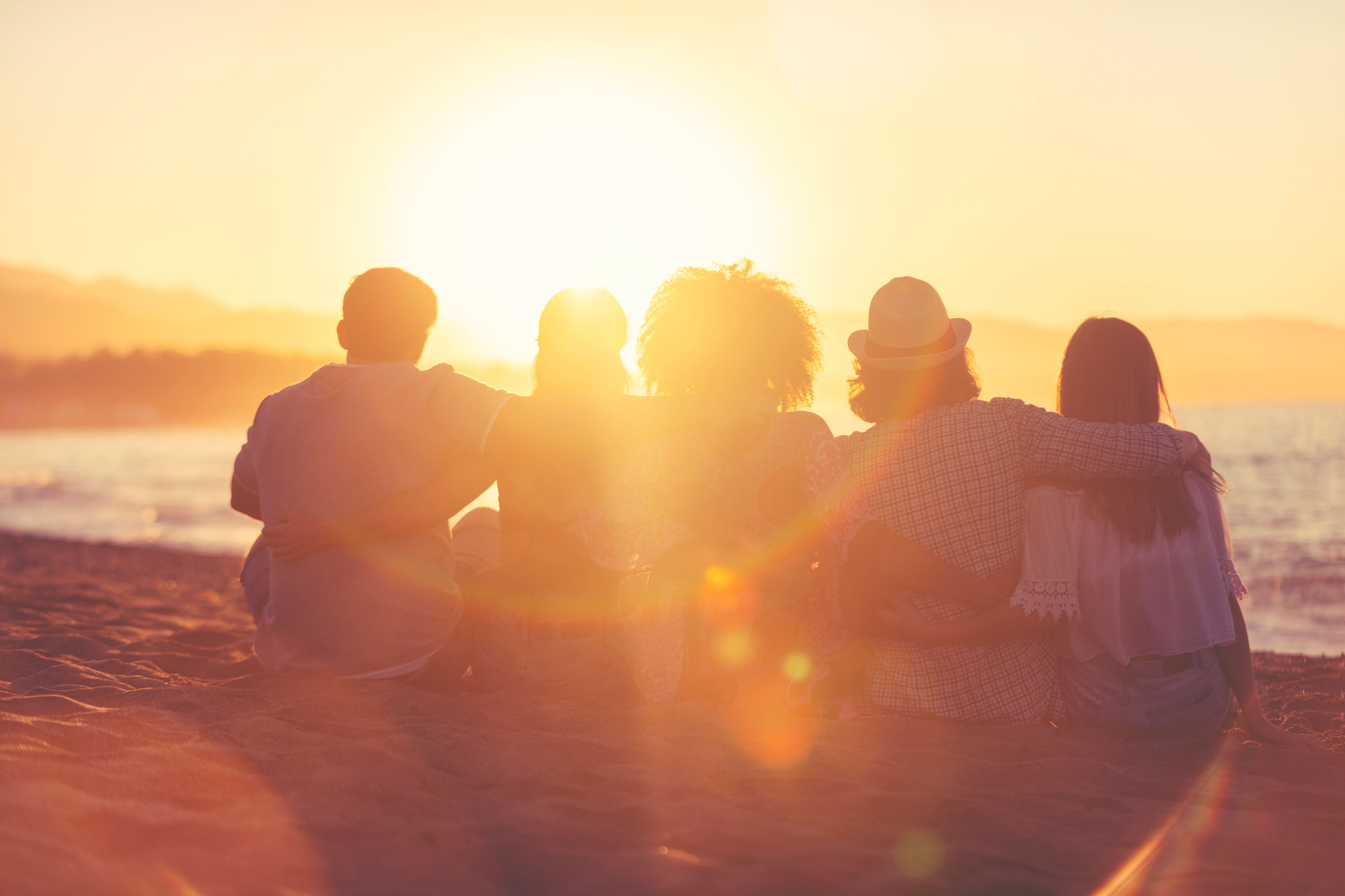 Group of friends sitting on the beach at sunset/sunrise. Group of friends sitting on the beach at sunset/sunrise.